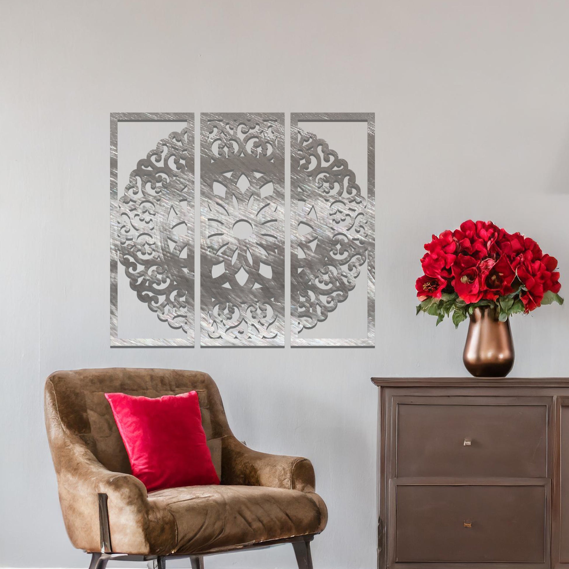 A metal wall art design split into three panels, featuring an intricate floral mandala pattern. The decorative piece is displayed on a neutral wall, adding an elegant, modern touch to the room's decor.
