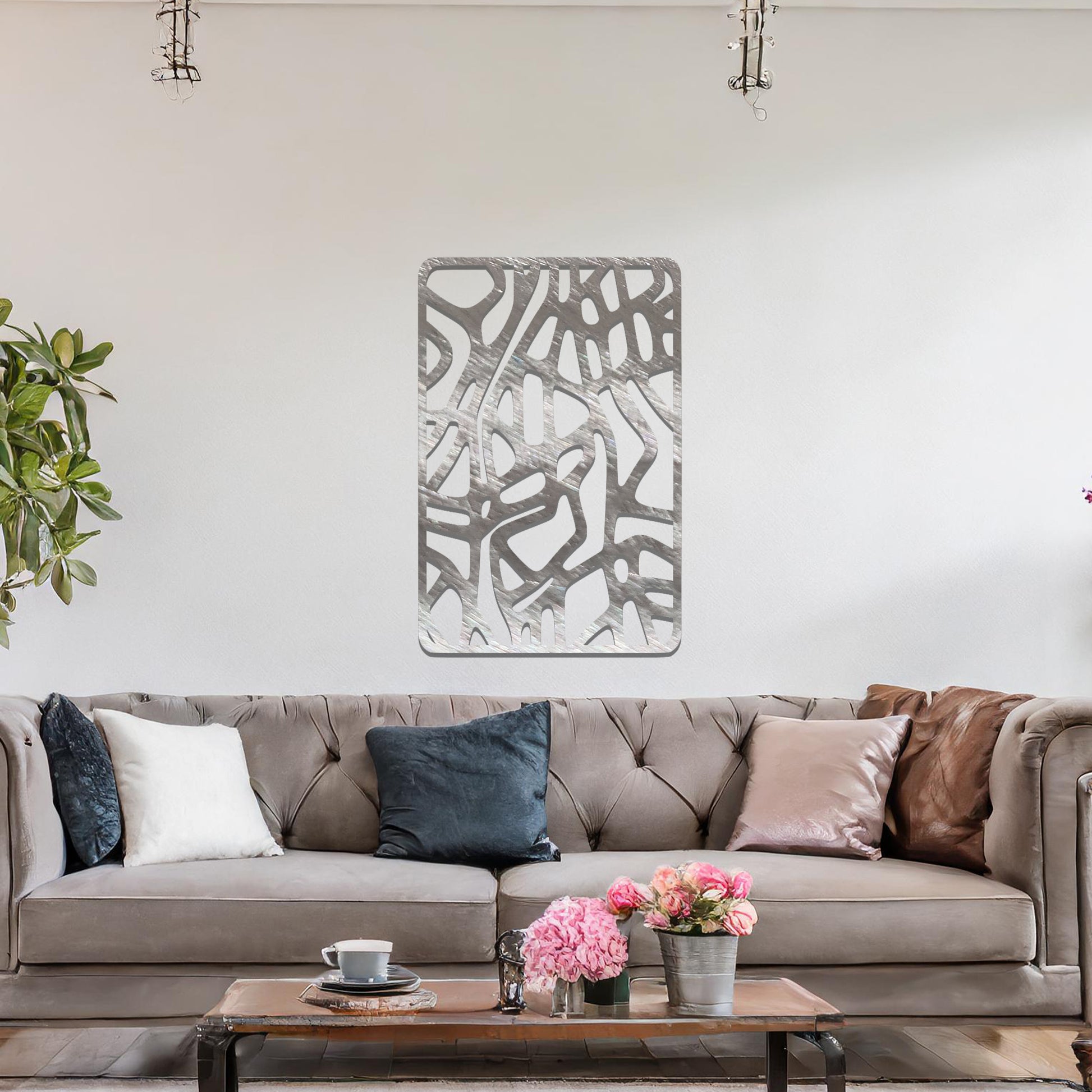 Metal wall art featuring an abstract design with interconnected lines and shapes, creating an organic pattern. The art is placed on a neutral wall within modern living room decor, enhancing the contemporary style of the space.