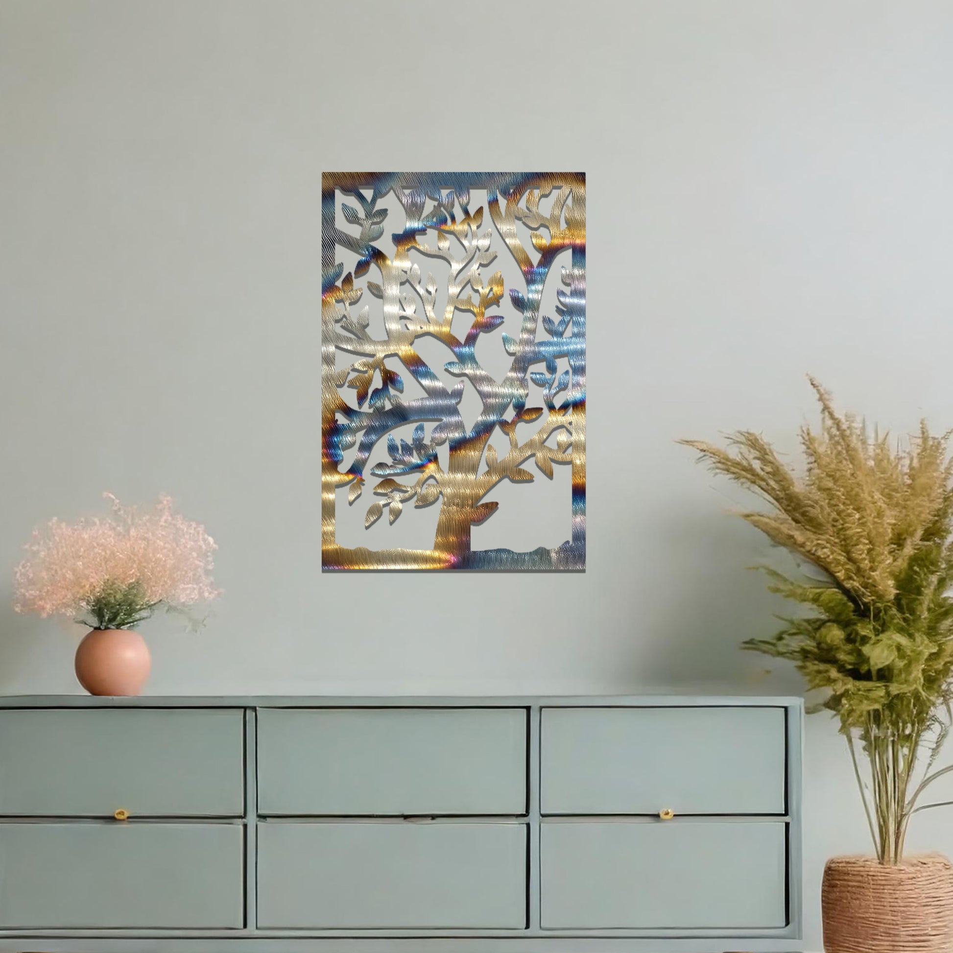 Metal wall art featuring a tree with detailed branches and leaves, enclosed in a rectangular frame. The artwork is displayed on a neutral wall within a modern office space, complemented by a stylish desk, chair, and greenery.