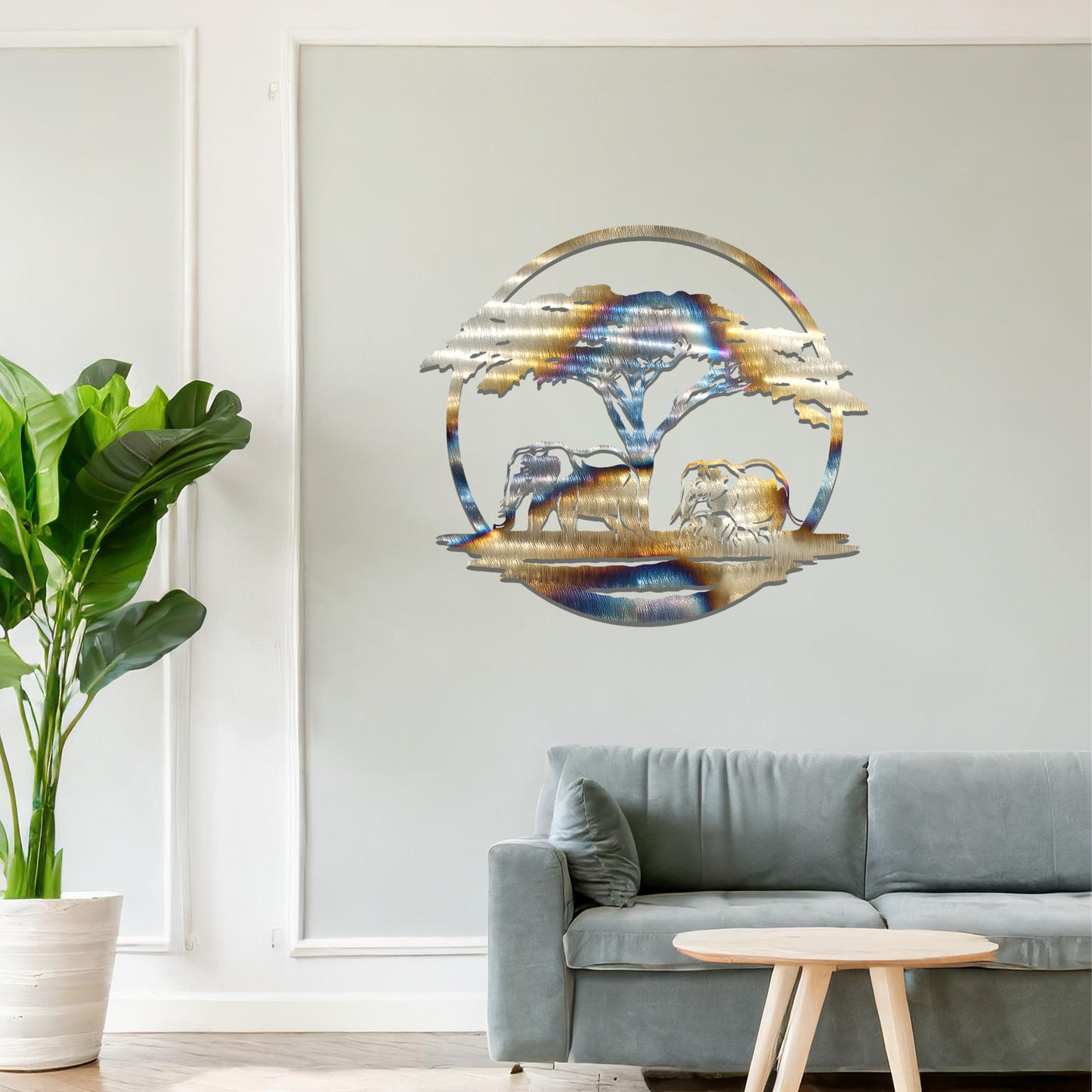 Metal wall art featuring a design of two elephants beneath a tree, framed in a circular shape. The art is placed on a neutral wall within modern room decor, creating a serene and nature-inspired atmosphere.