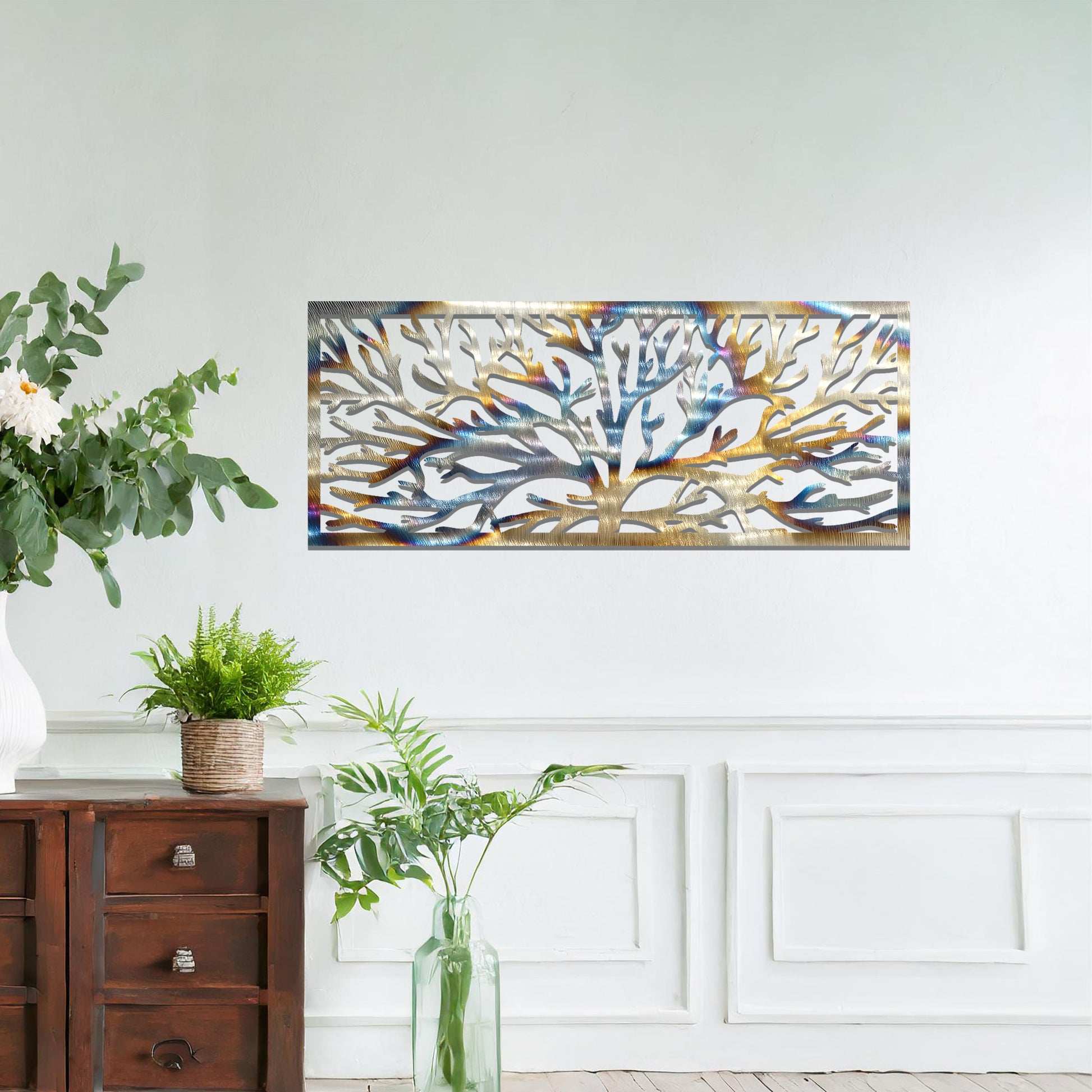 A metal wall art design featuring a detailed tree silhouette with sprawling branches, enclosed in a rectangular frame. The art is displayed on a neutral wall in a modern living room, complementing the contemporary decor and natural elements in the space.