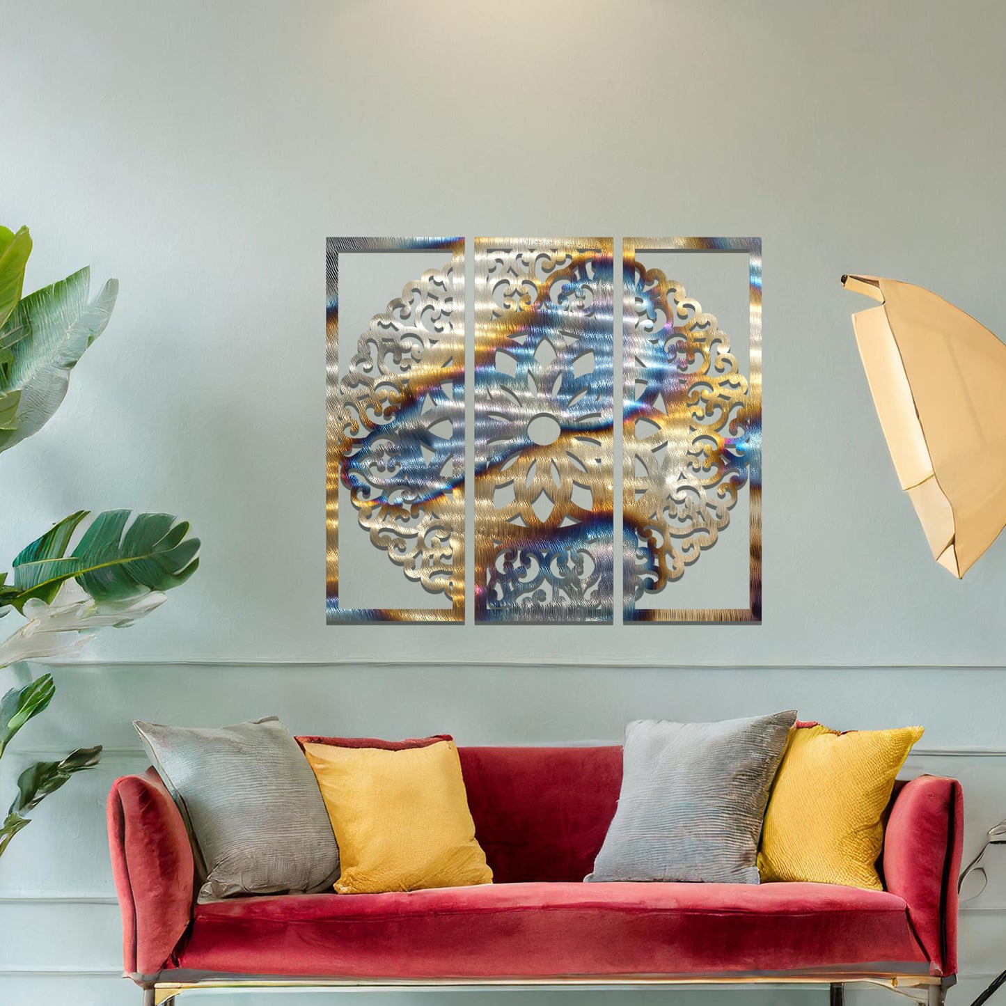 A metal wall art design split into three panels, featuring an intricate floral mandala pattern. The decorative piece is displayed on a neutral wall, adding an elegant, modern touch to the room's decor.