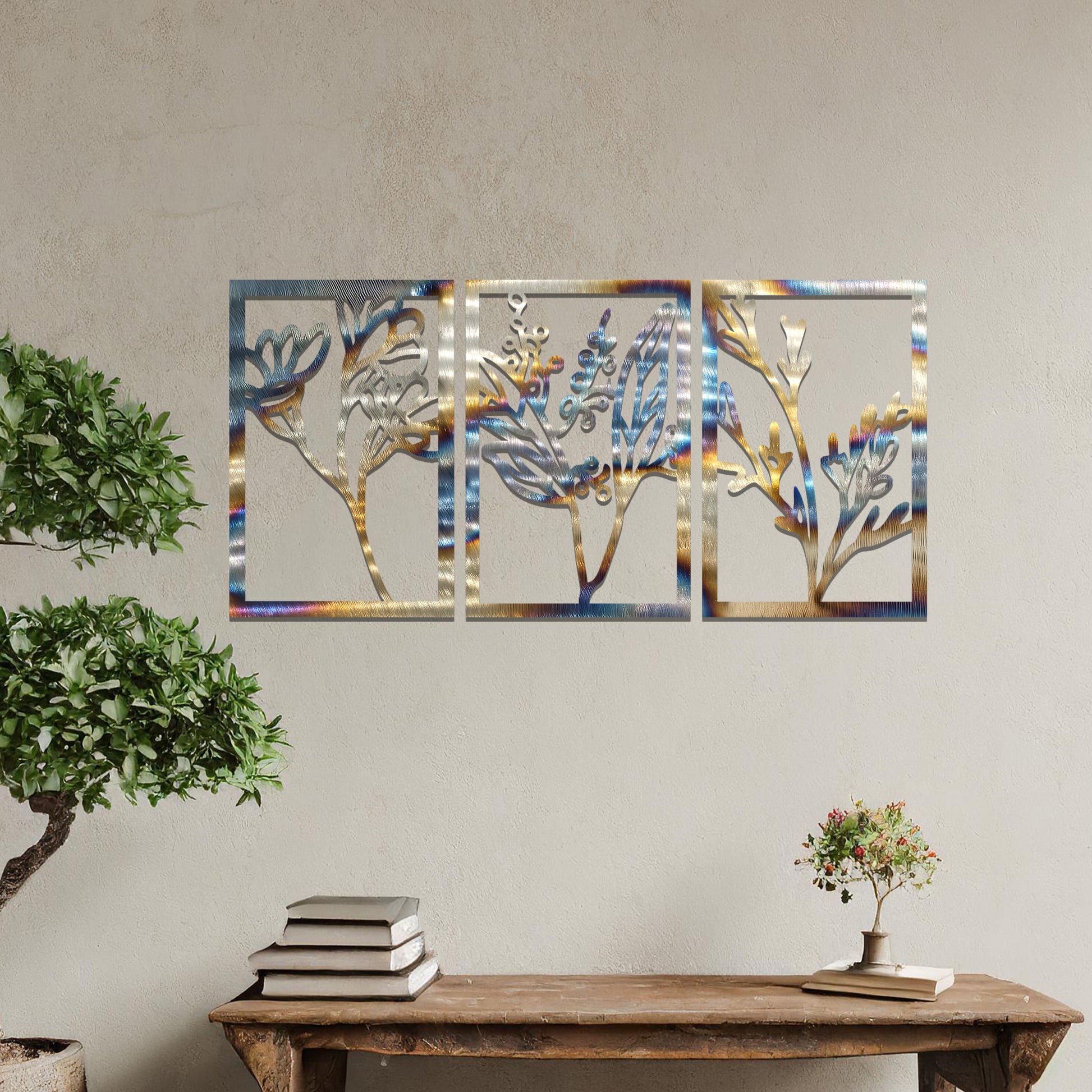 A set of three metal panels featuring intricate botanical designs, with delicate plant shapes in a flowing pattern. The artwork is placed on a neutral wall, enhancing the natural, calming atmosphere of the modern living space.