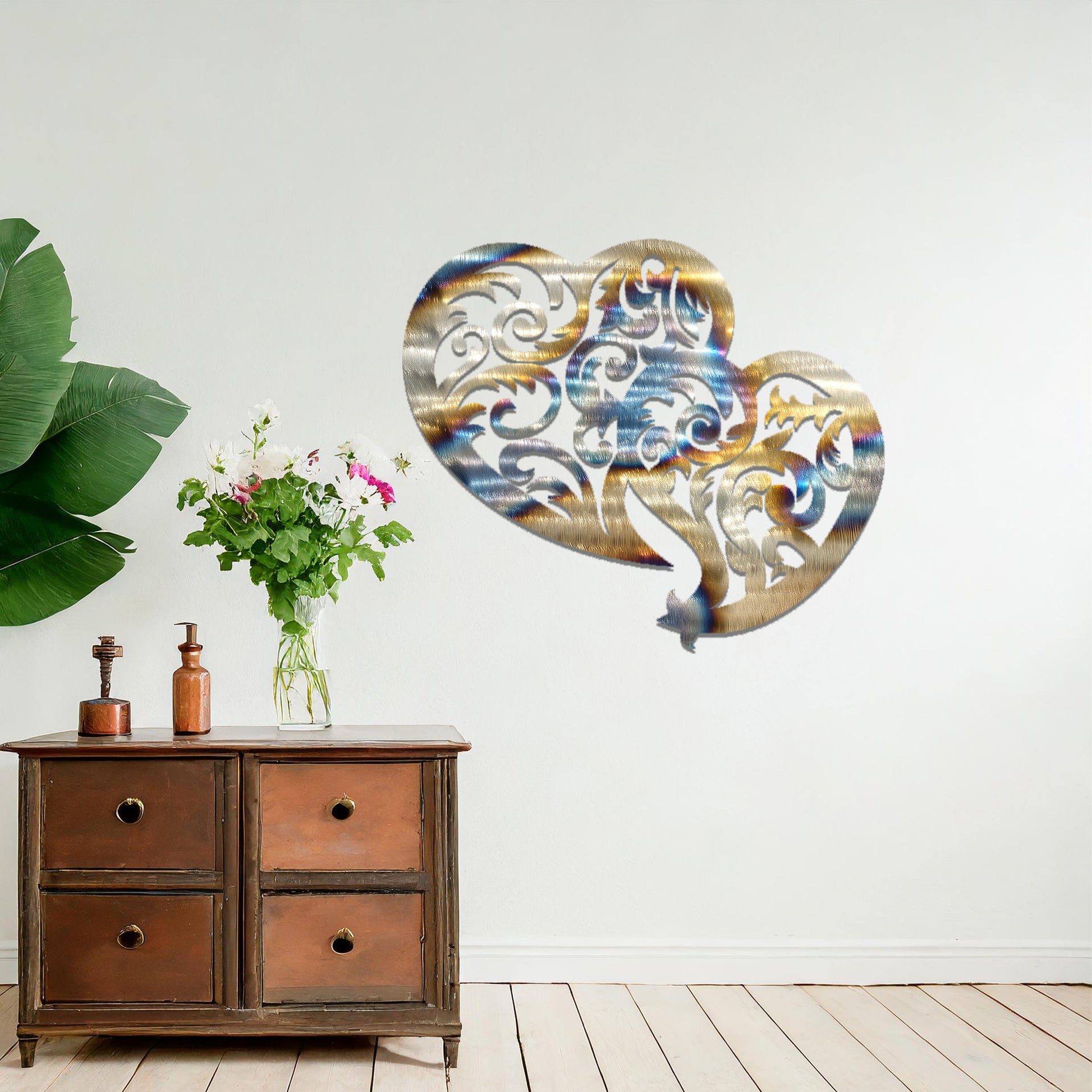Metal wall art featuring a pair of intricately designed hearts with swirling patterns, mounted on a neutral wall within modern room decor. The elegant detailing creates a romantic and artistic focal point, adding a touch of love to the space.