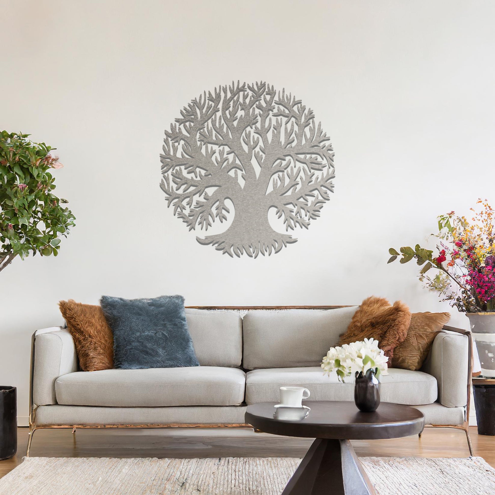Metal wall art featuring a circular tree design with intricate branches and roots, crafted with precise laser-cut detailing, placed on a neutral wall within modern decor.