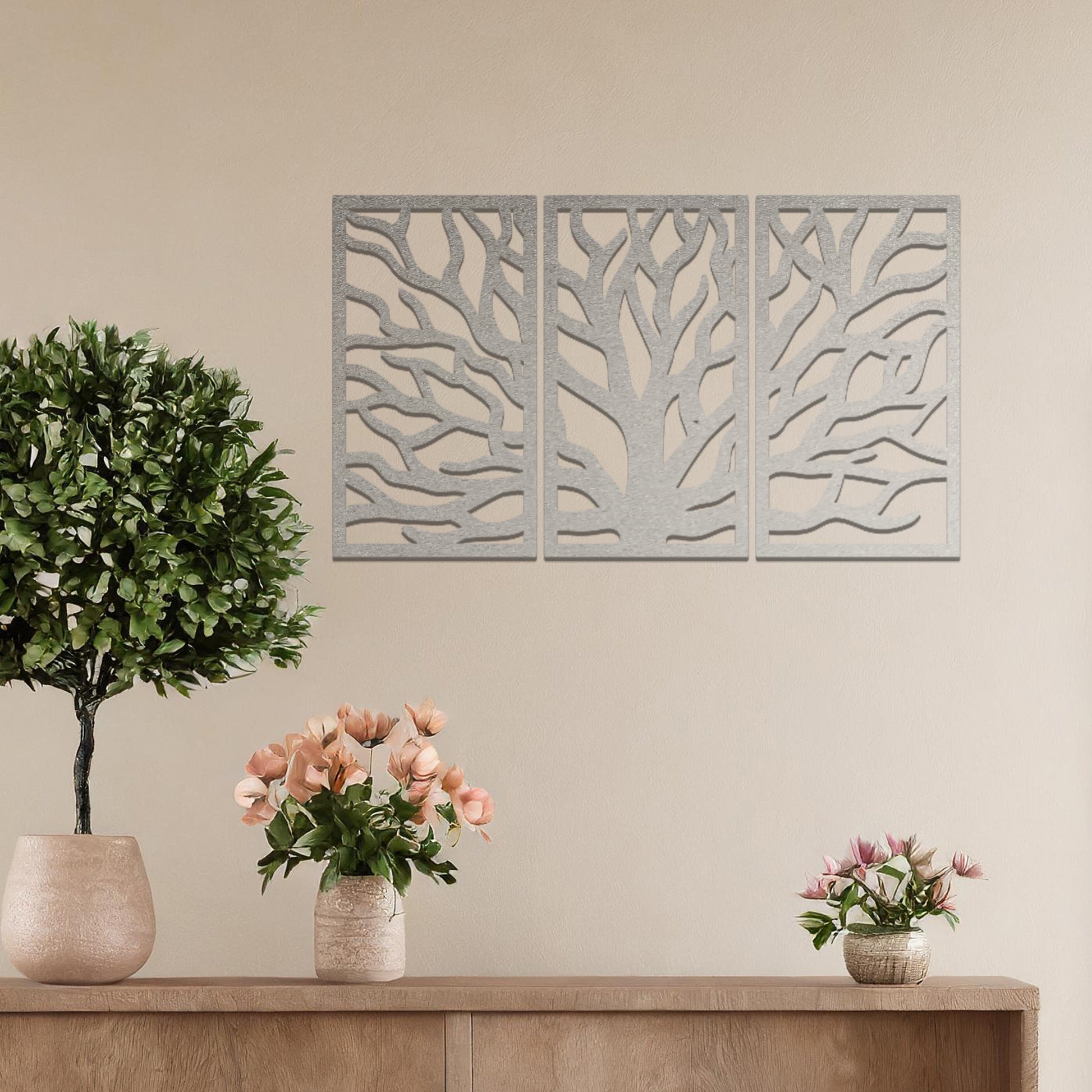 Metal wall art featuring a three-panel design of a tree with intricate branching patterns, crafted with precise laser-cut detailing, placed on a neutral wall within modern decor.