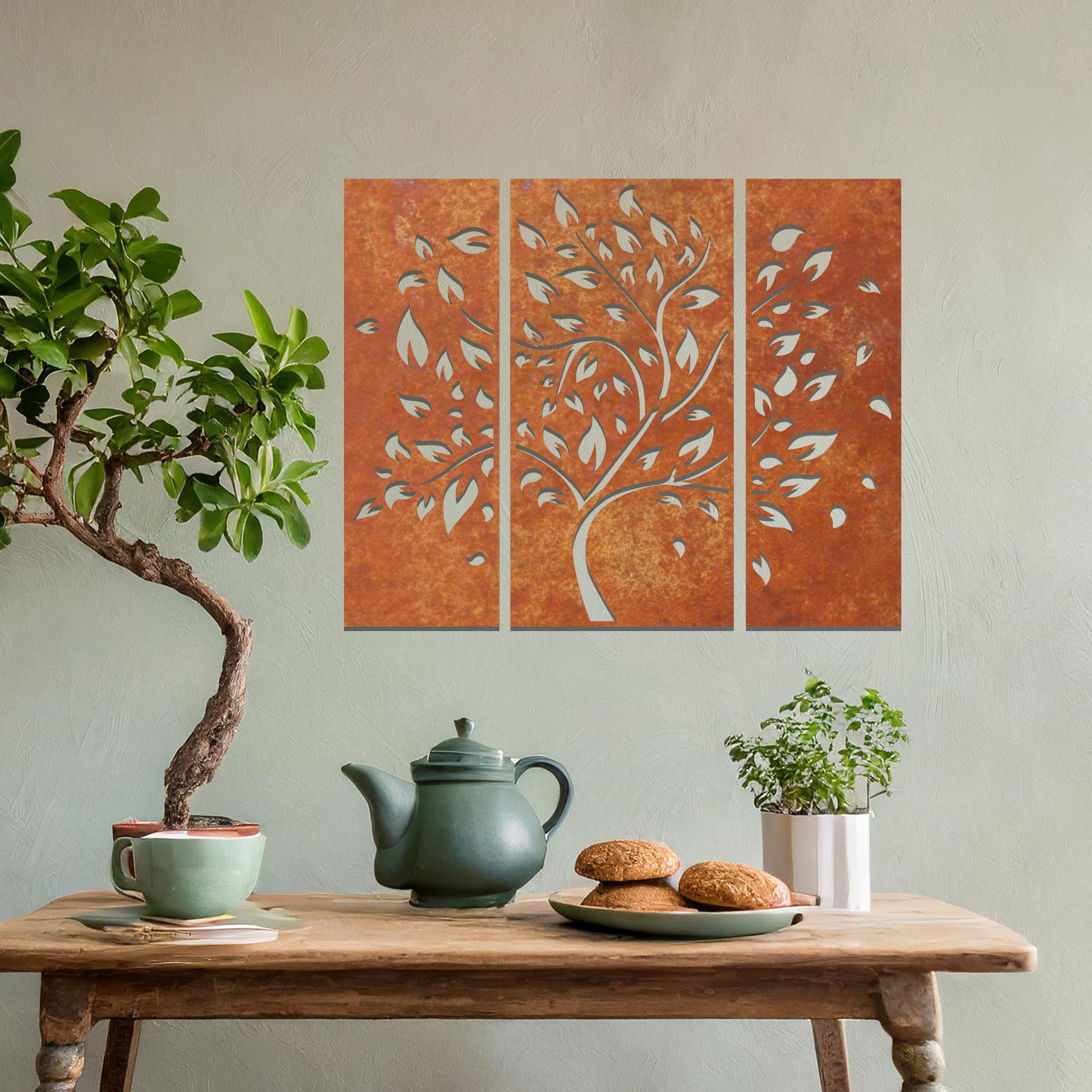 Metal wall art featuring a three-panel tree design with curved branches and delicate leaves, crafted with precise laser-cut detailing, displayed on a neutral wall within modern decor.