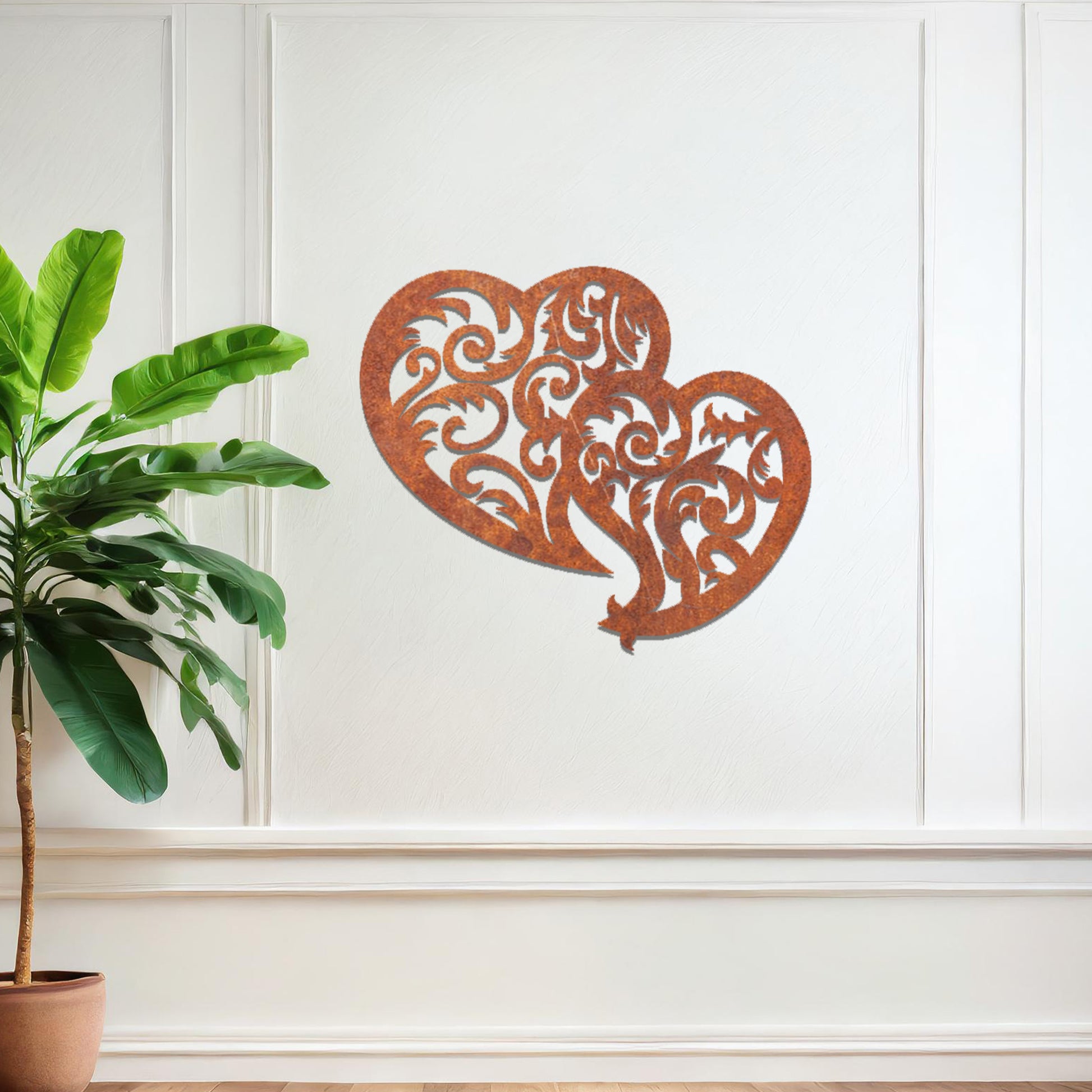 Metal wall art featuring a pair of intricately designed hearts with swirling patterns, mounted on a neutral wall within modern room decor. The elegant detailing creates a romantic and artistic focal point, adding a touch of love to the space.