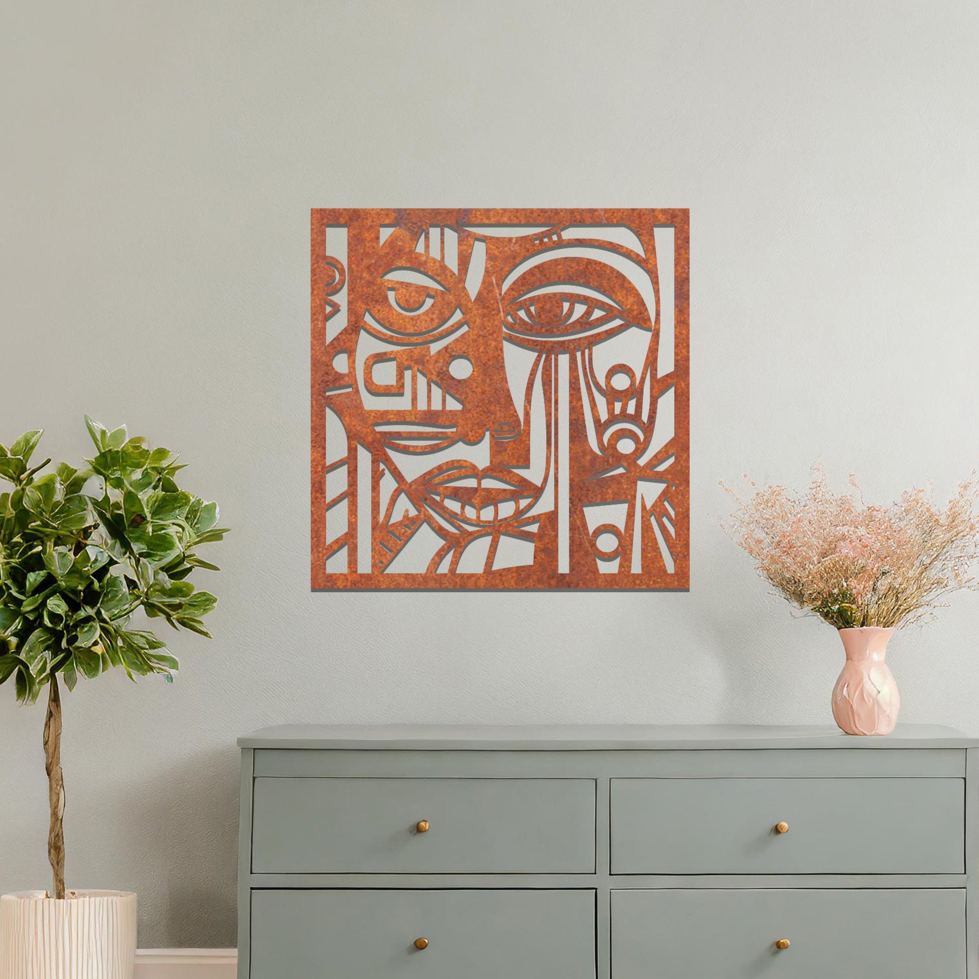 A metal wall art design featuring an abstract face with geometric shapes and sharp lines. The face's features are creatively outlined with strong contrasts, adding a modern, artistic touch to the space. The piece is displayed on a neutral wall, enhancing the room’s decor.