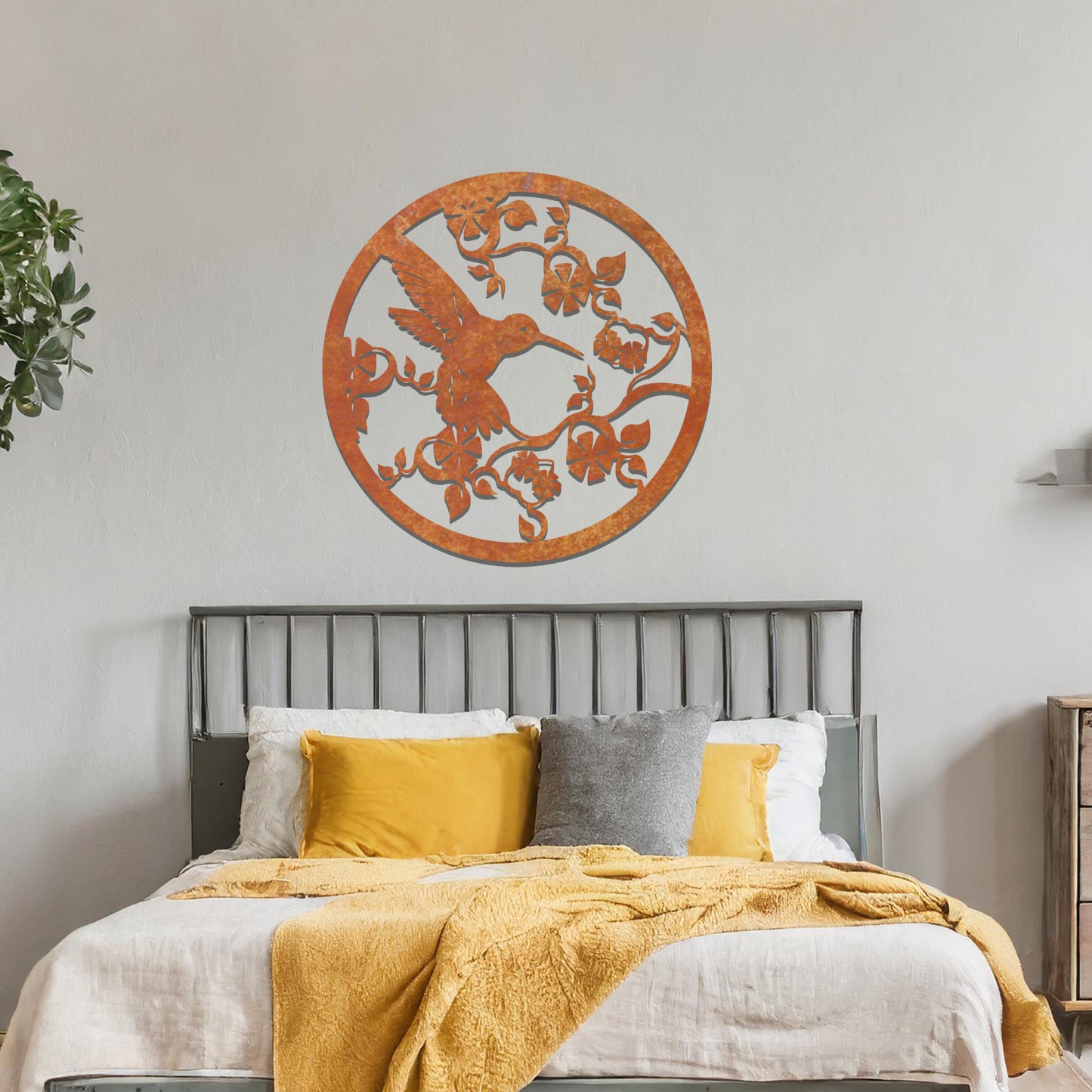 Metal wall art featuring a bird perched on floral vines in a circular design. The intricate patterns of the leaves and branches are beautifully balanced, creating a harmonious look. The art is placed on a neutral wall within modern room decor.