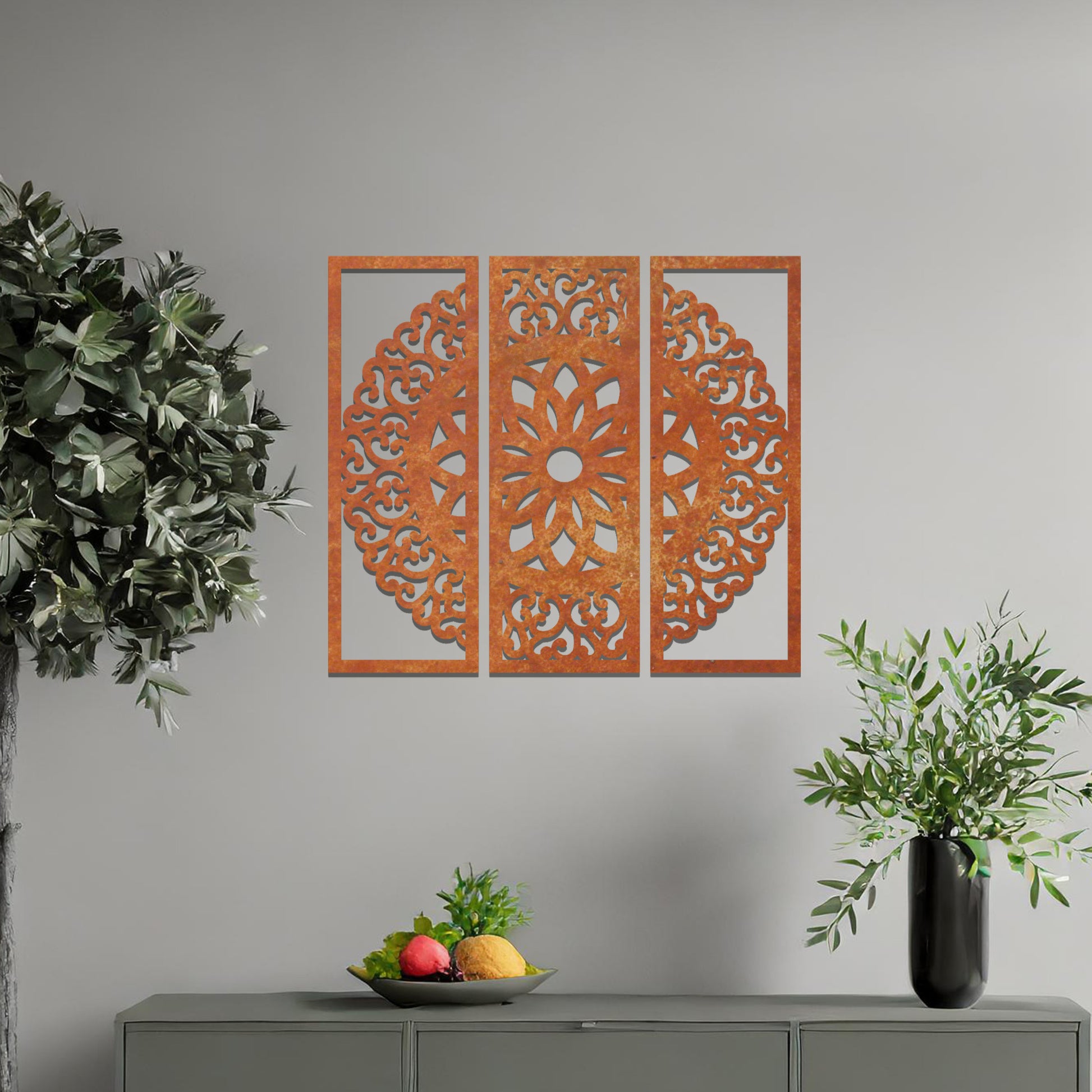 A metal wall art design split into three panels, featuring an intricate floral mandala pattern. The decorative piece is displayed on a neutral wall, adding an elegant, modern touch to the room's decor.