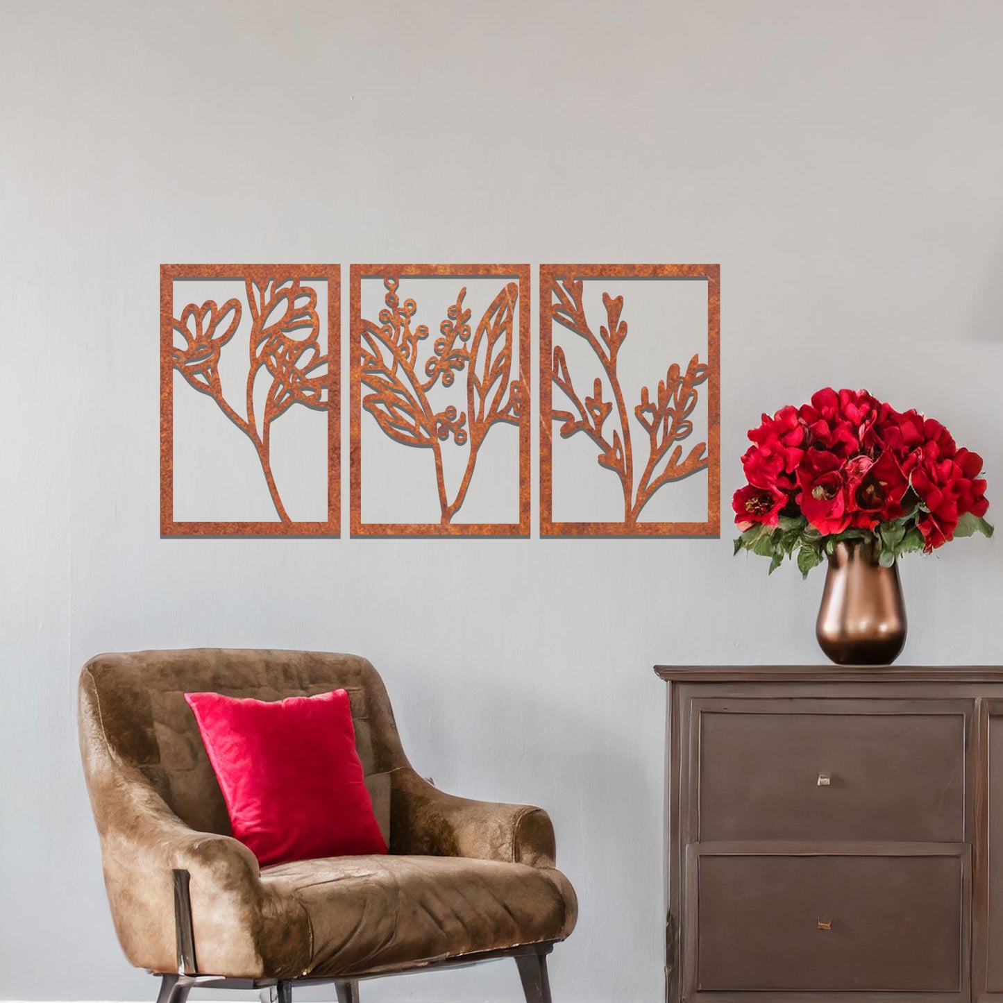 A set of three metal panels featuring intricate botanical designs, with delicate plant shapes in a flowing pattern. The artwork is placed on a neutral wall, enhancing the natural, calming atmosphere of the modern living space.