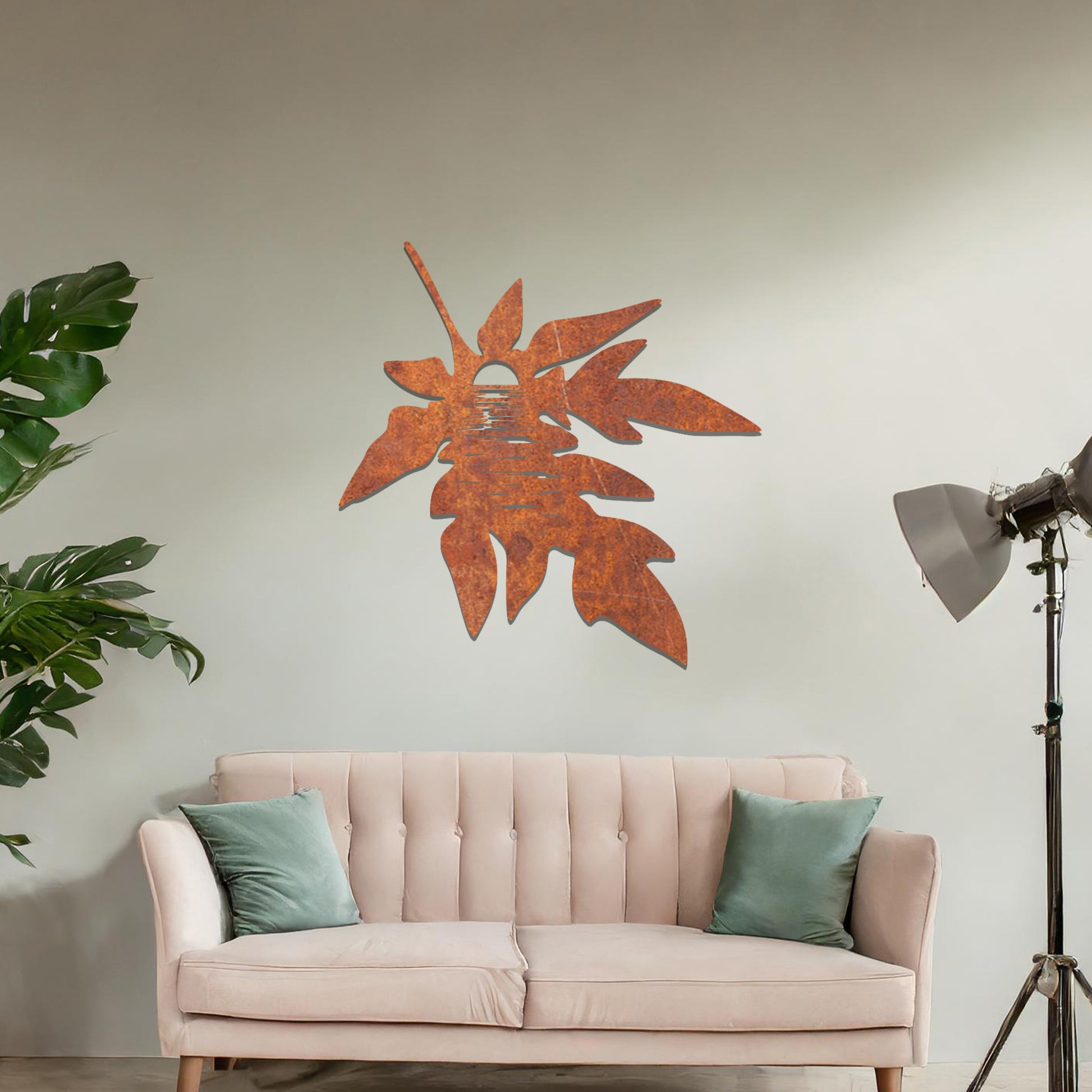 Metal wall art featuring a stylised leaf design with intricate line details, incorporating a circular motif resembling the sun or moon, mounted on a neutral wall. The organic form and minimalist design add a serene and artistic touch to the space.