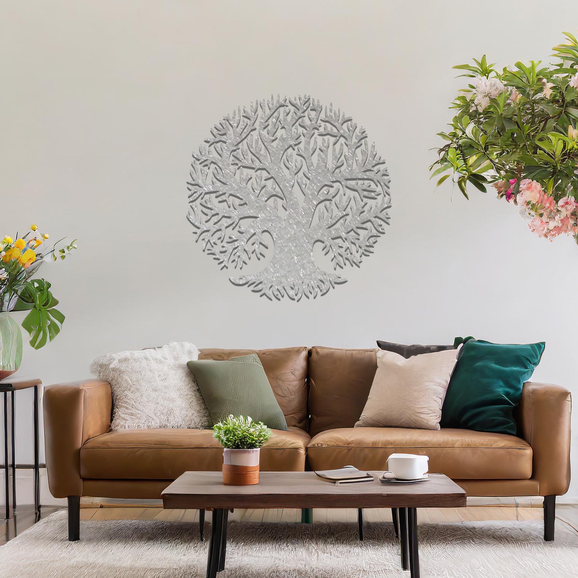 Metal wall art featuring a circular tree design with intricate branches and roots, crafted with precise laser-cut detailing, placed on a neutral wall within modern decor.