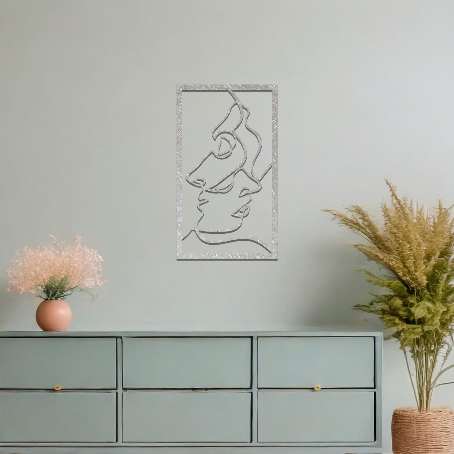 Metal wall art featuring an abstract design of two faces in profile, formed with flowing lines. The art is placed on a neutral wall within a modern office setting, contributing to a stylish and contemporary atmosphere.