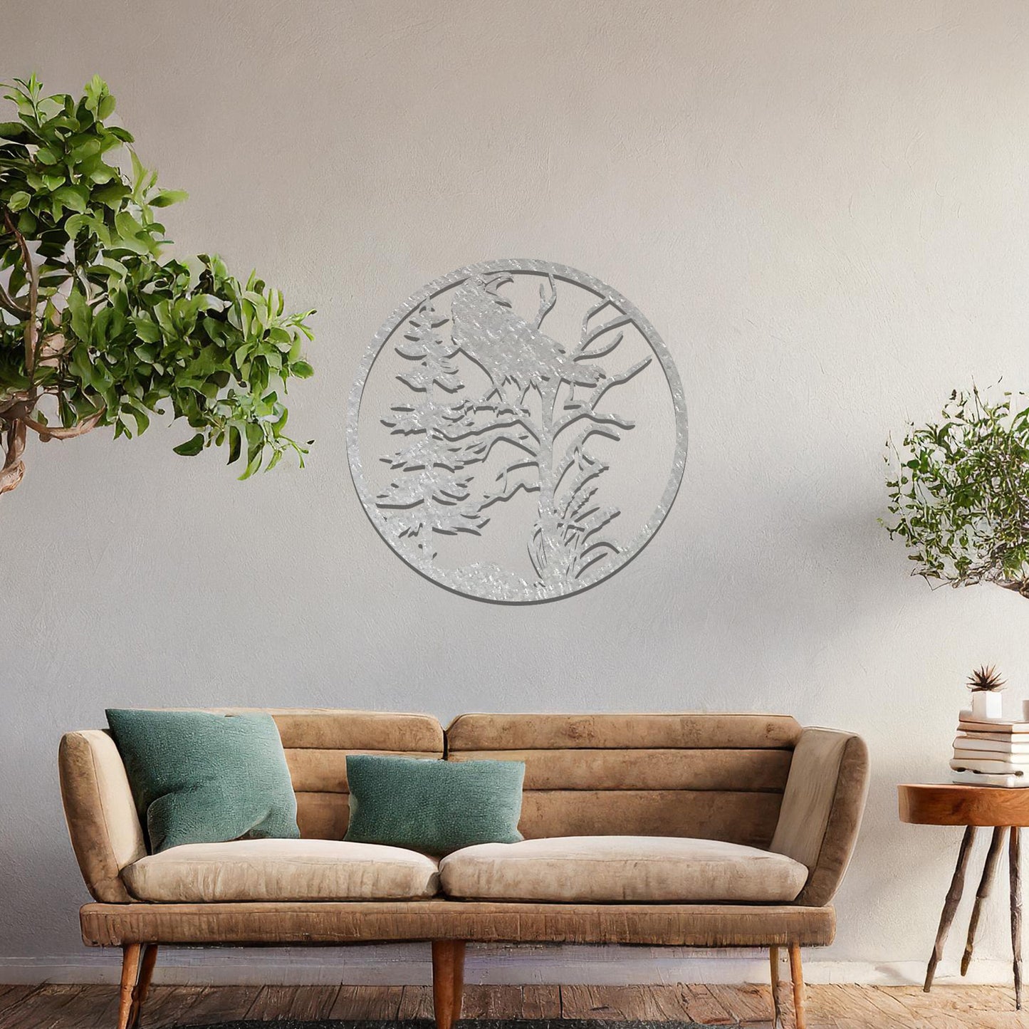 Metal wall art featuring a circular design with a silhouette of a raven perched on a tree branch, surrounded by trees and foliage, mounted on a neutral wall within modern room decor. The intricate detailing and natural motif create a bold and artistic focal point in the space.