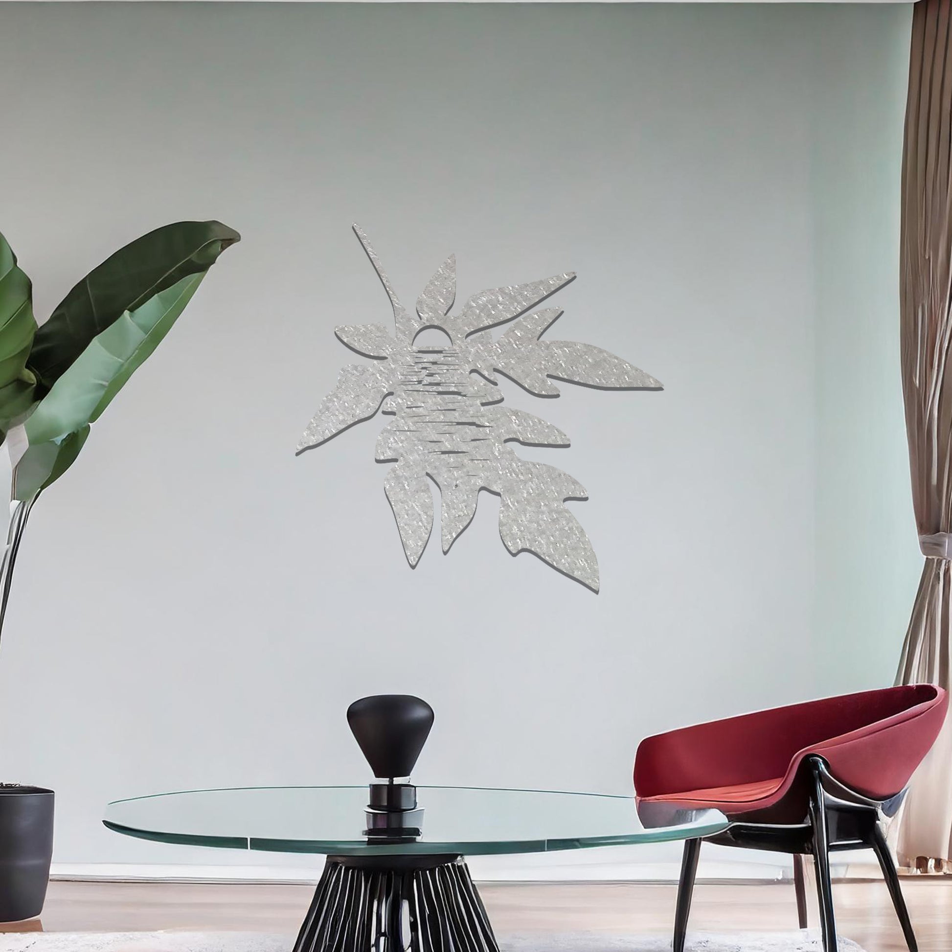 Metal wall art featuring a stylised leaf design with intricate line details, incorporating a circular motif resembling the sun or moon, mounted on a neutral wall. The organic form and minimalist design add a serene and artistic touch to the space.
