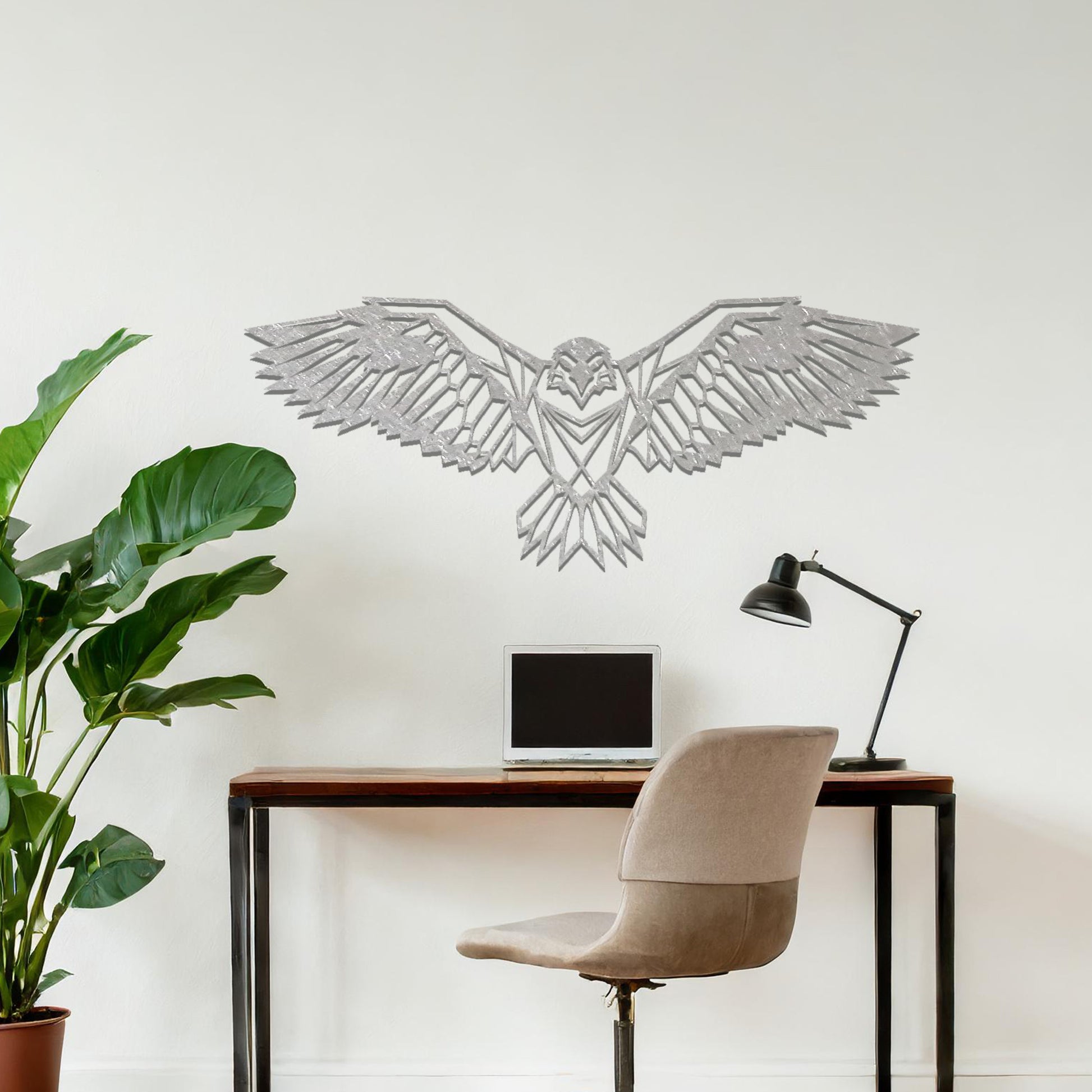Metal wall art featuring a geometric eagle design with outstretched wings and intricate detailing, crafted with precise laser-cut techniques, displayed on a neutral wall within modern decor.
