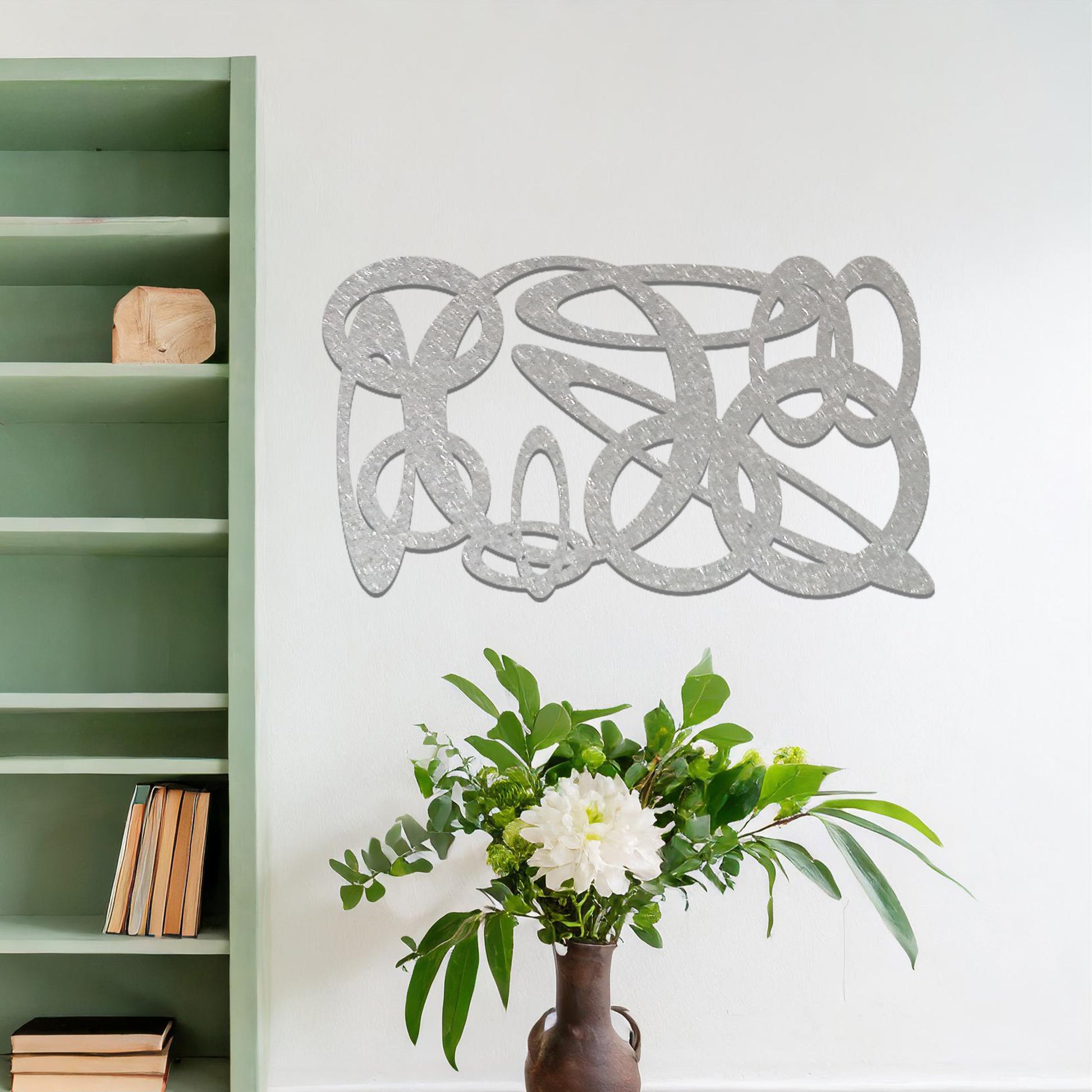 Metal wall art featuring a dynamic, abstract design with overlapping loops and curves. The art is placed on a neutral wall within modern room decor, creating a bold and fluid statement in the space.