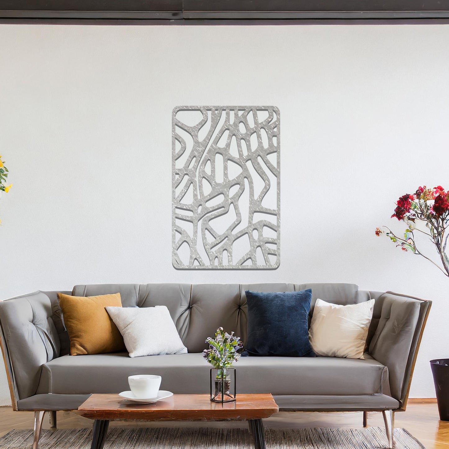 Metal wall art featuring an abstract design with interconnected lines and shapes, creating an organic pattern. The art is placed on a neutral wall within modern living room decor, enhancing the contemporary style of the space.