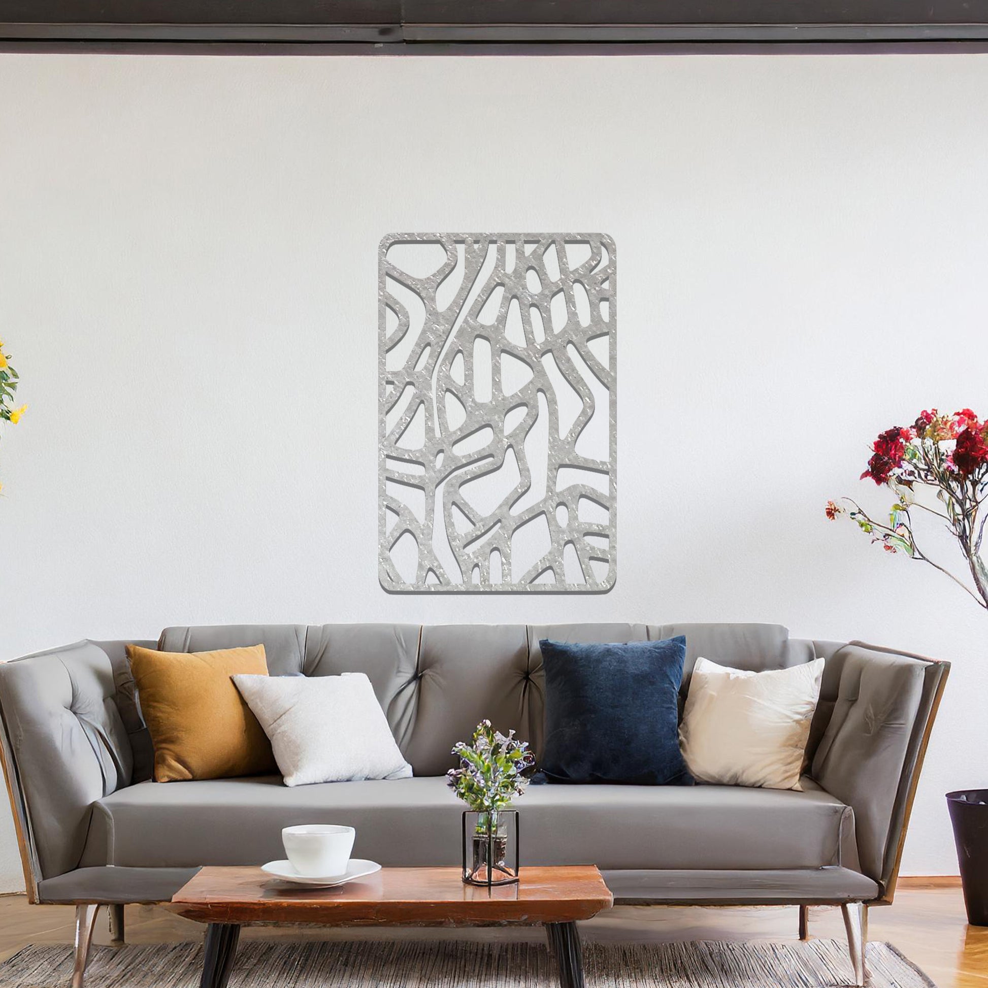 Metal wall art featuring an abstract design with interconnected lines and shapes, creating an organic pattern. The art is placed on a neutral wall within modern living room decor, enhancing the contemporary style of the space.