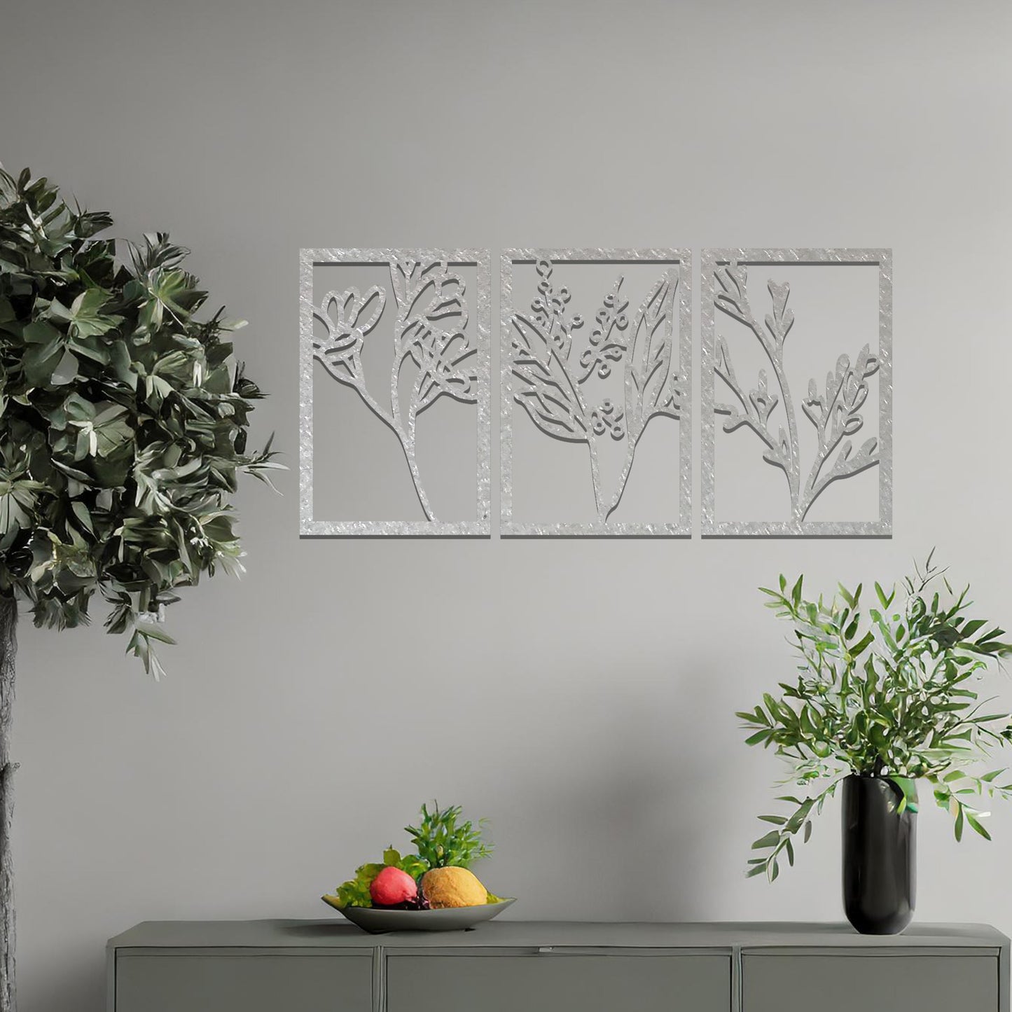 A set of three metal panels featuring intricate botanical designs, with delicate plant shapes in a flowing pattern. The artwork is placed on a neutral wall, enhancing the natural, calming atmosphere of the modern living space.