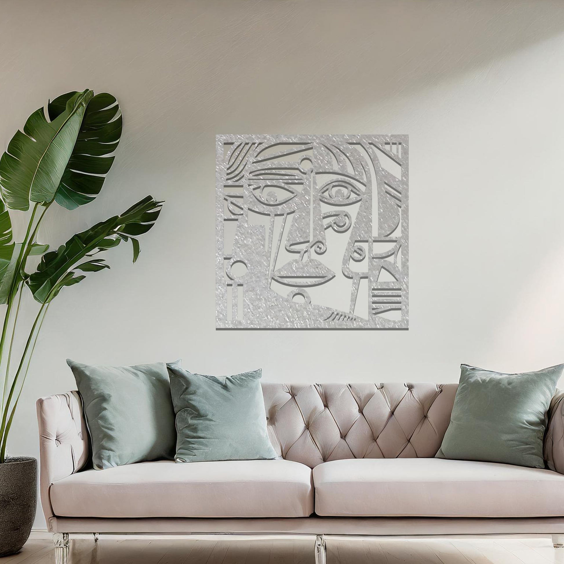 Geometric abstract face design cut from metal. The face features bold lines, sharp angles, and circular elements, creating a unique artistic representation. The art is displayed on a neutral wall in a modern room setting.
