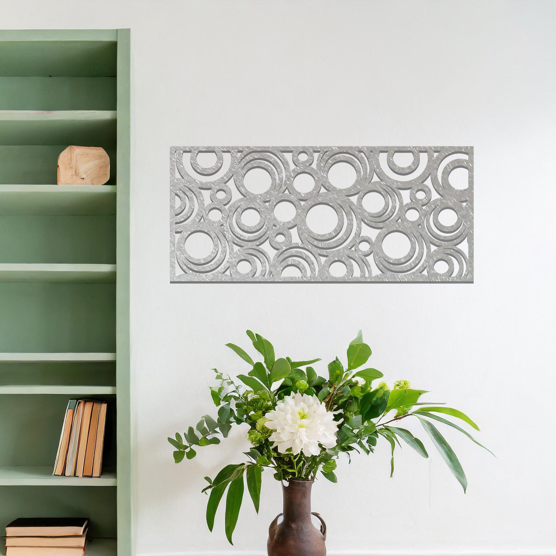 Metal wall art featuring an intricate pattern of overlapping circles in various sizes. The design is set against a neutral wall in a modern living room space, adding a touch of contemporary elegance to the decor.