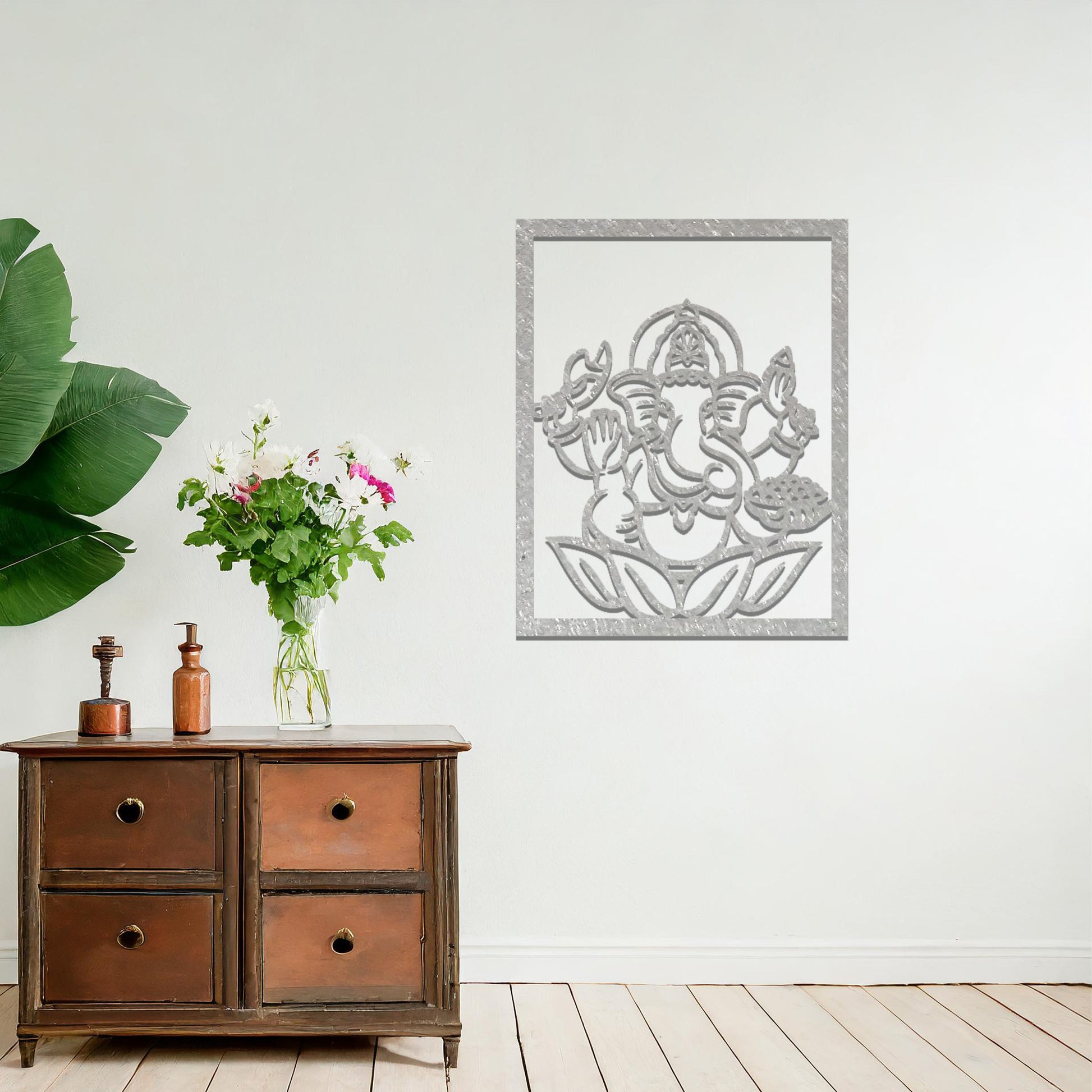 Metal wall art featuring a rectangular design of Lord Ganesha sitting on a lotus, showcasing intricate detailing of the deity's form and symbolic elements, mounted on a neutral wall within modern room decor. The craftsmanship adds a spiritual and artistic touch to the space.