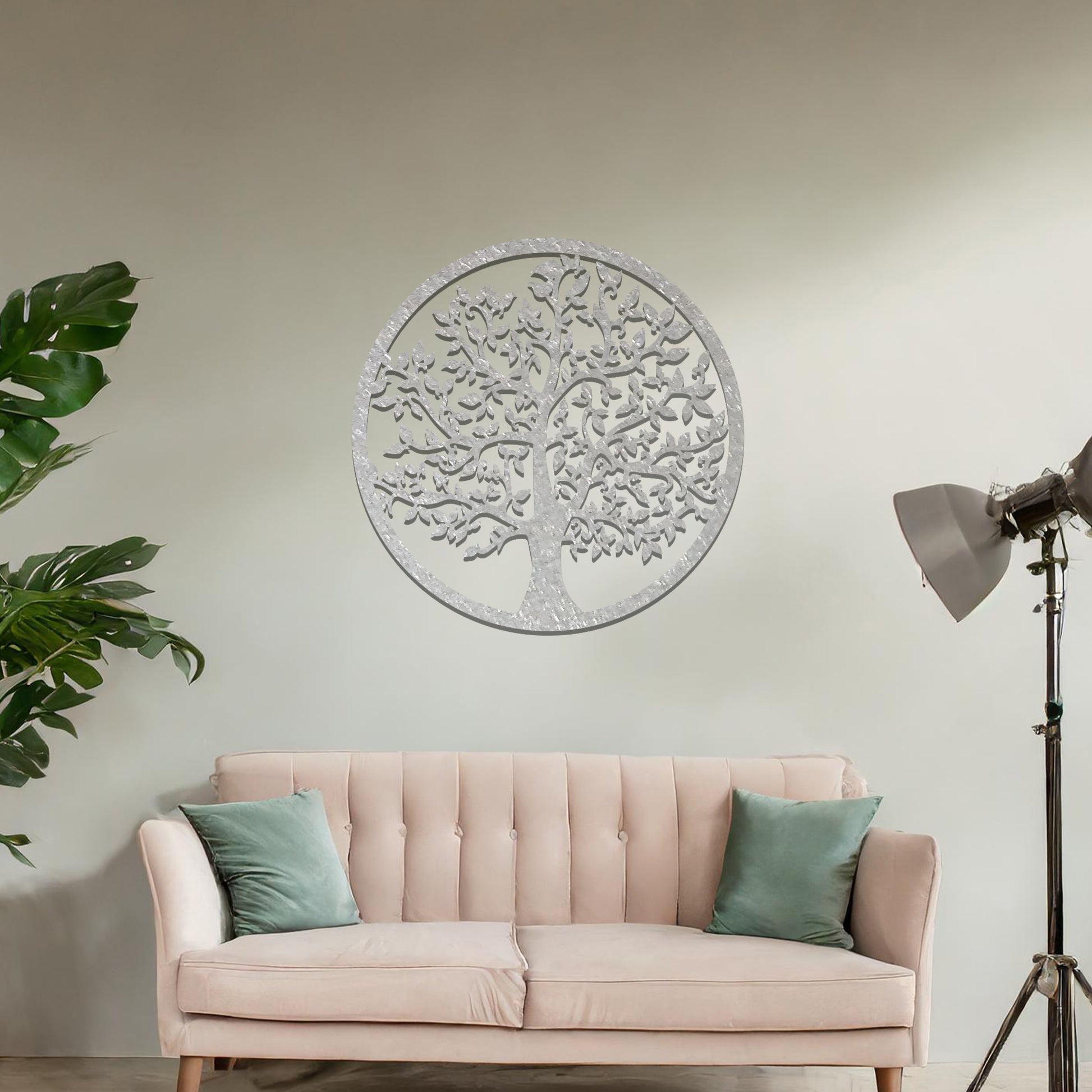 Metal wall art featuring a circular design with a detailed tree of life motif, showcasing intricate branches and leaves, mounted on a neutral wall within modern room decor. The elegant craftsmanship and symbolic design add a touch of sophistication and meaning to the space.