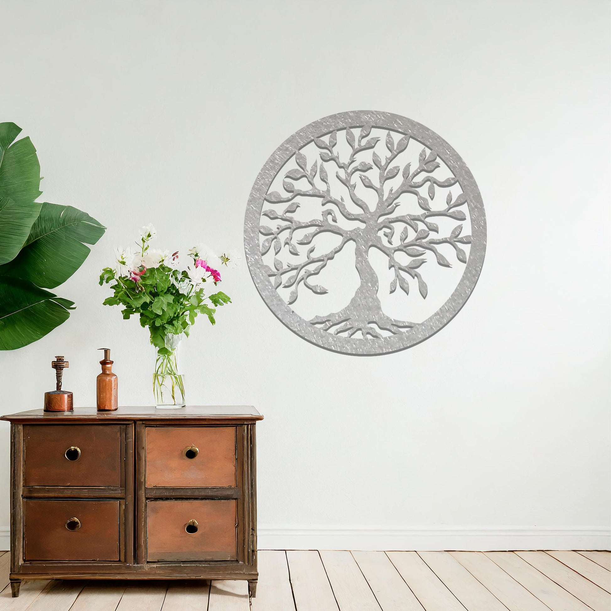 Metal wall art featuring a circular tree of life design with intricate branches and leaves, mounted on a neutral wall within modern bedroom decor. The detailed craftsmanship and symbolic motif create a calming and elegant focal point in the room.