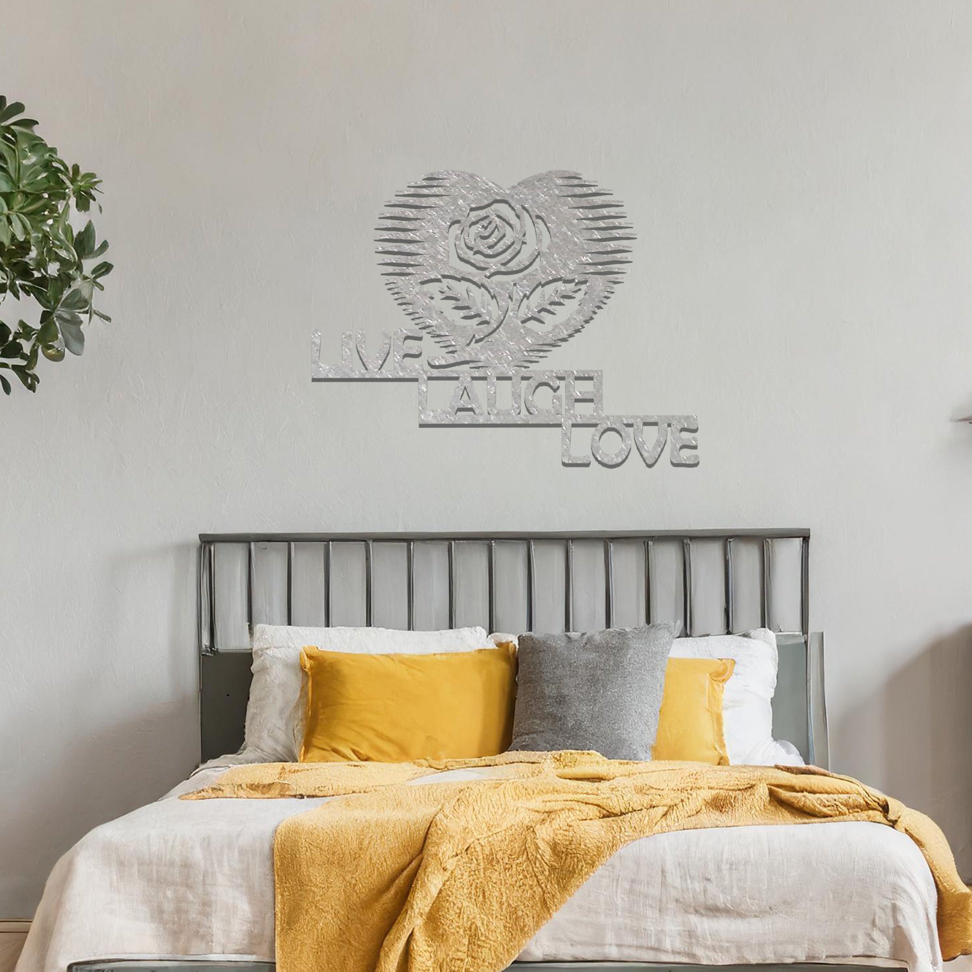 Metal wall art featuring the words "LIVE LAUGH LOVE" alongside a rose within a heart shape, with bold lines and intricate design. The art is displayed on a neutral wall within modern room decor, offering a stylish and motivational accent to the space.
