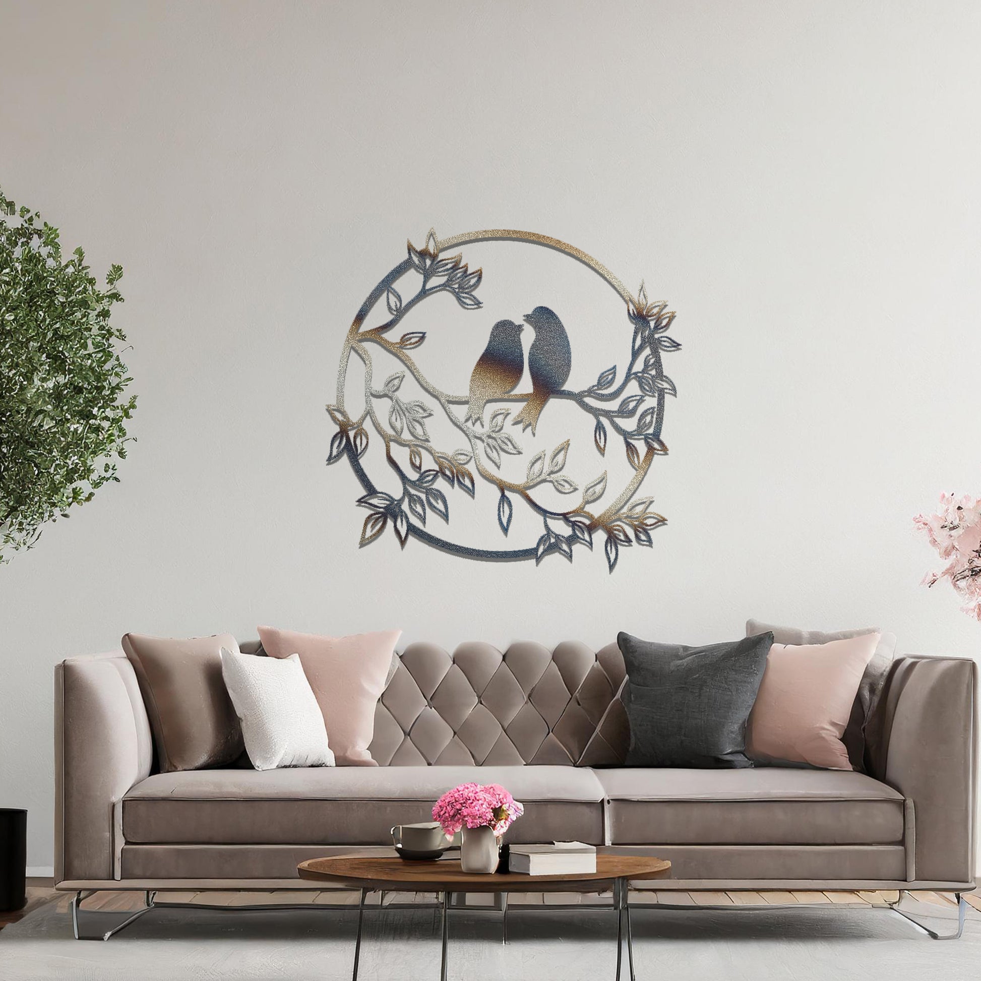 Metal wall art featuring a circular design with two birds perched on a branch surrounded by intricate leaves, adding a charming focal point to a beautifully styled living space.