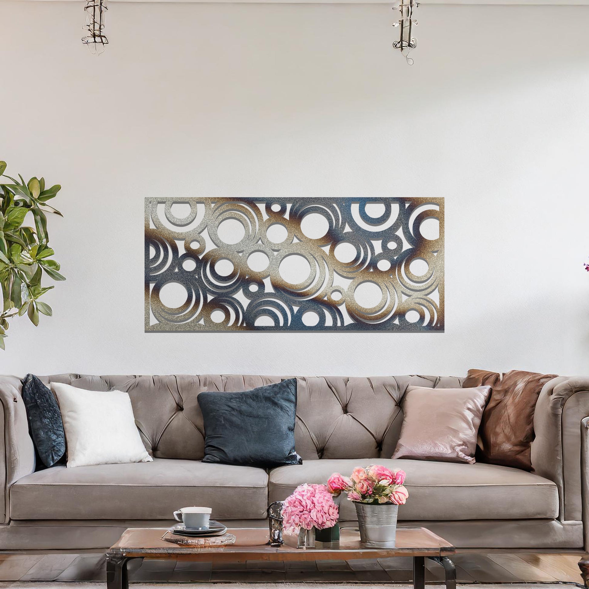 Metal wall art featuring an intricate pattern of overlapping circles in various sizes. The design is set against a neutral wall in a modern living room space, adding a touch of contemporary elegance to the decor.