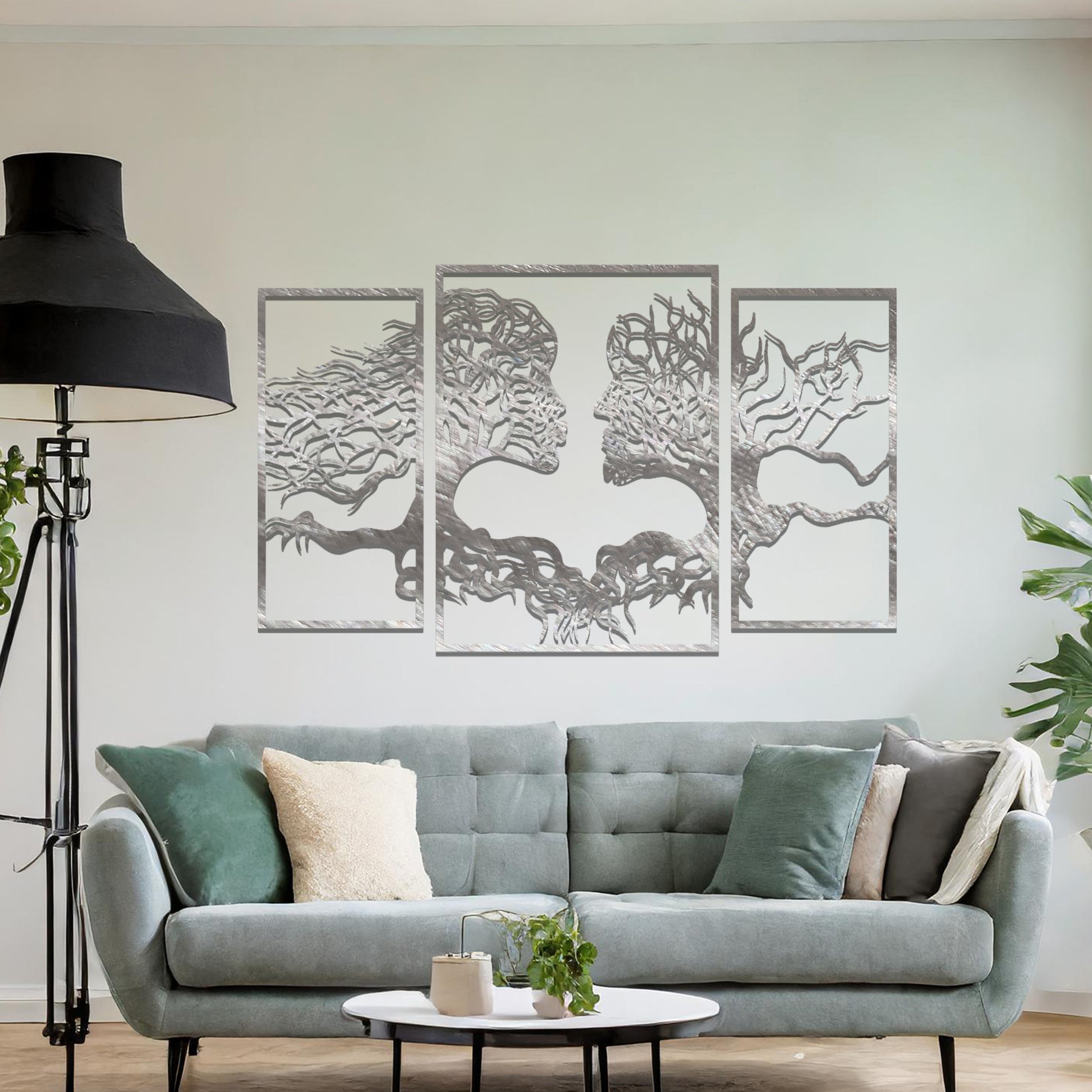 Metal wall art featuring an intricate design of two tree-like figures forming human profiles, crafted with precise laser-cut detailing, framed in panels and placed on a neutral wall within modern decor.