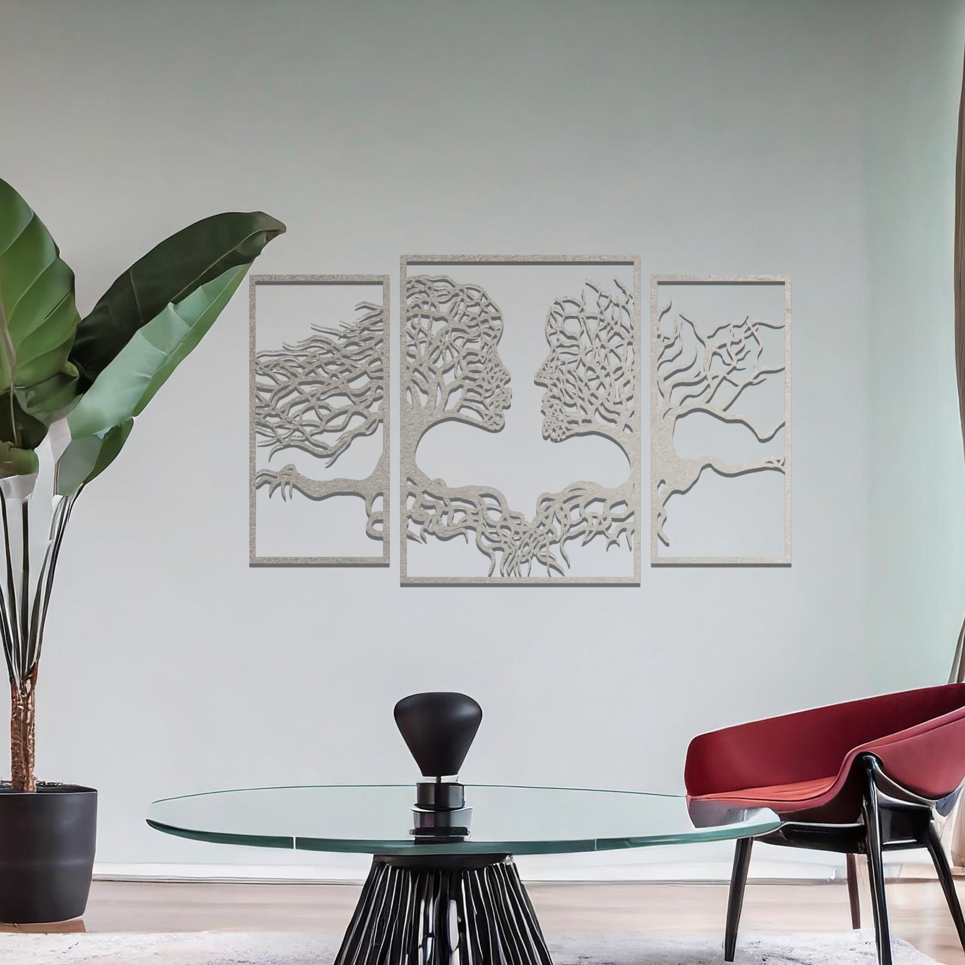 Metal wall art featuring an intricate design of two tree-like figures forming human profiles, crafted with precise laser-cut detailing, framed in panels and placed on a neutral wall within modern decor.