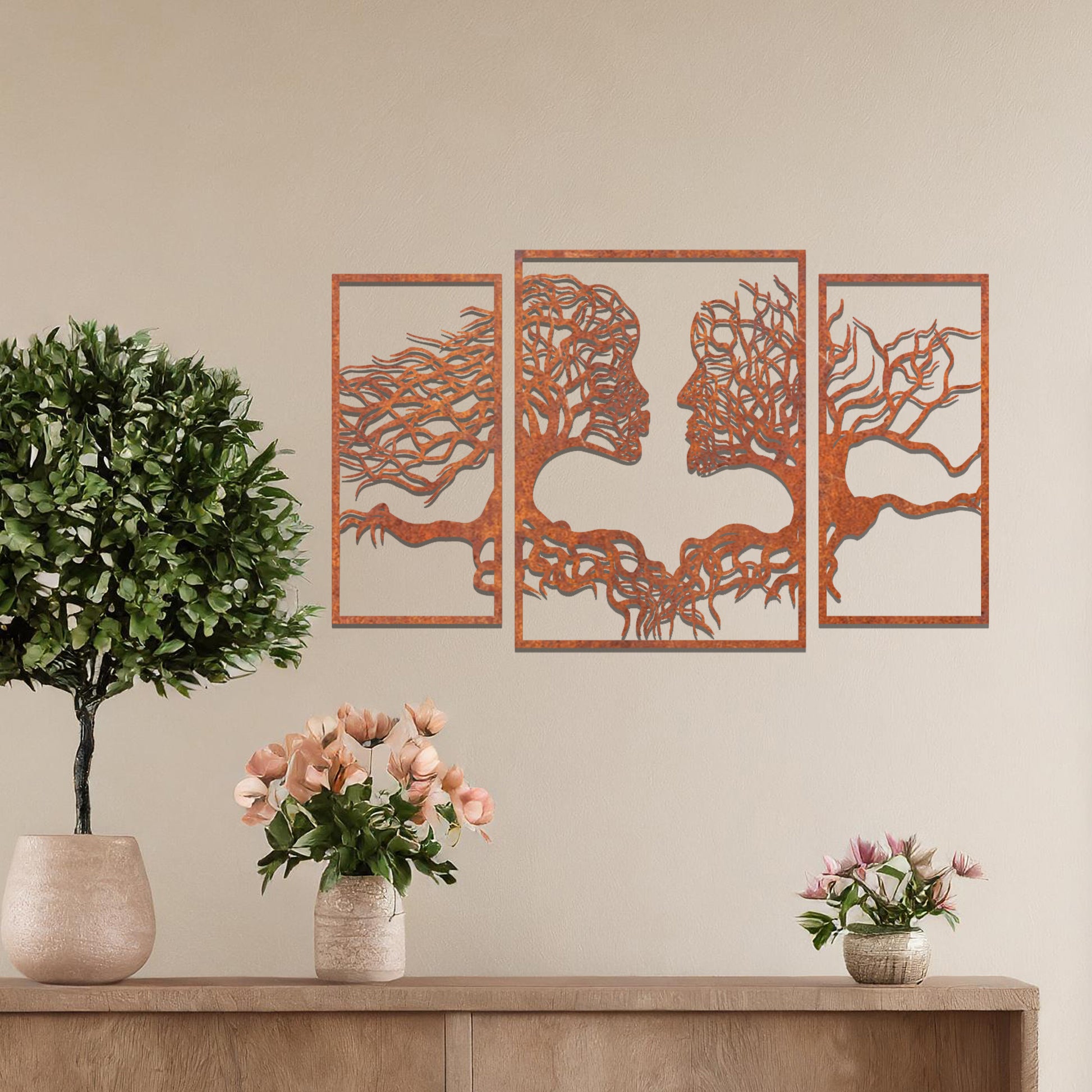Metal wall art featuring an intricate design of two tree-like figures forming human profiles, crafted with precise laser-cut detailing, framed in panels and placed on a neutral wall within modern decor.