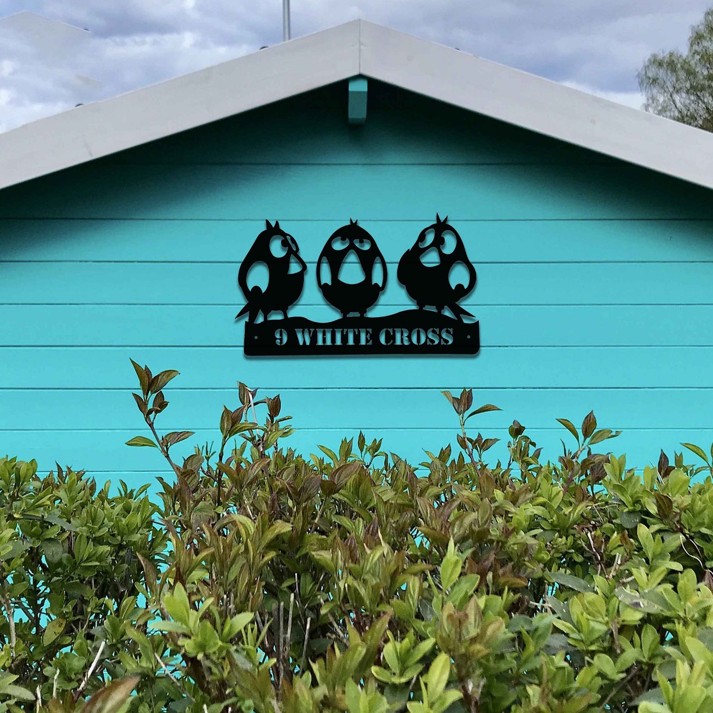 Metal garden decoration featuring three playful bird silhouettes perched on a customisable nameplate, adding a personalised and charming touch to outdoor walls, fences, or sheds.