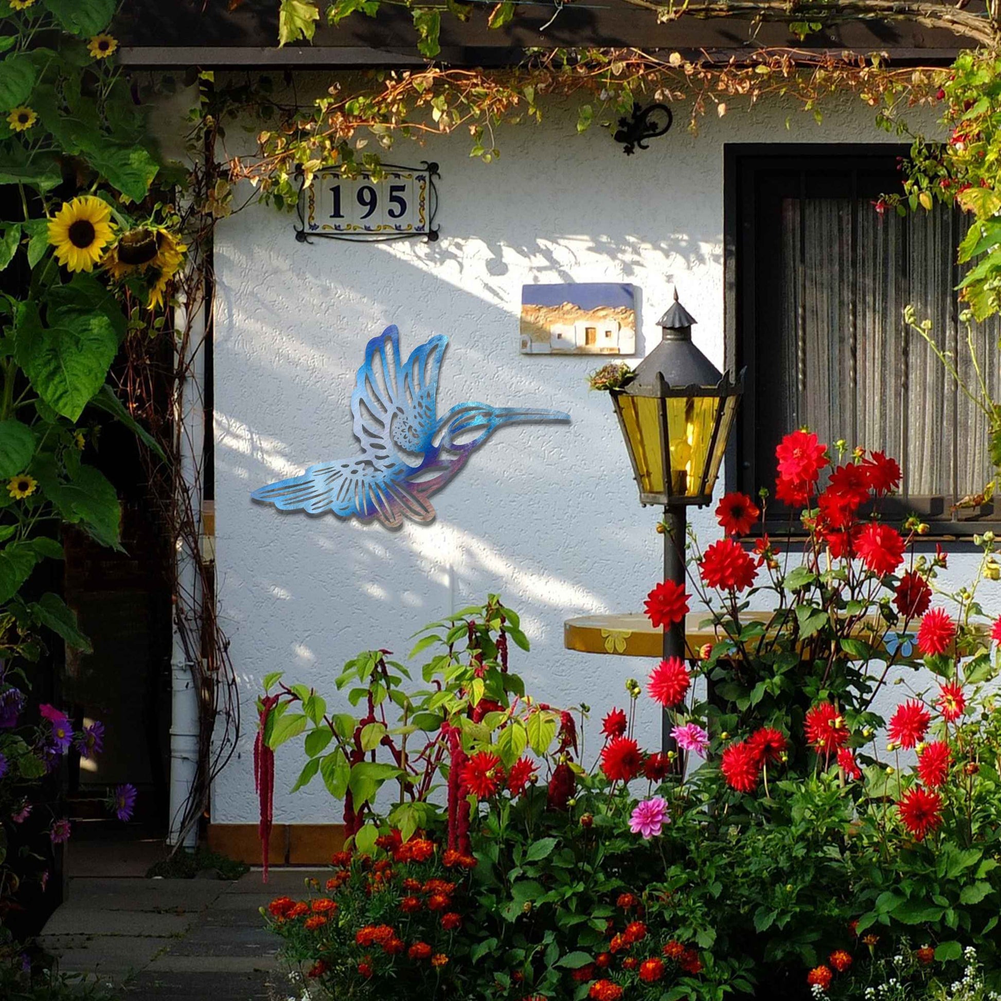 Metal garden decoration featuring a hummingbird in flight with intricate detailing, showcasing a rustic finish that adds a natural and artistic charm to outdoor walls or garden settings.
