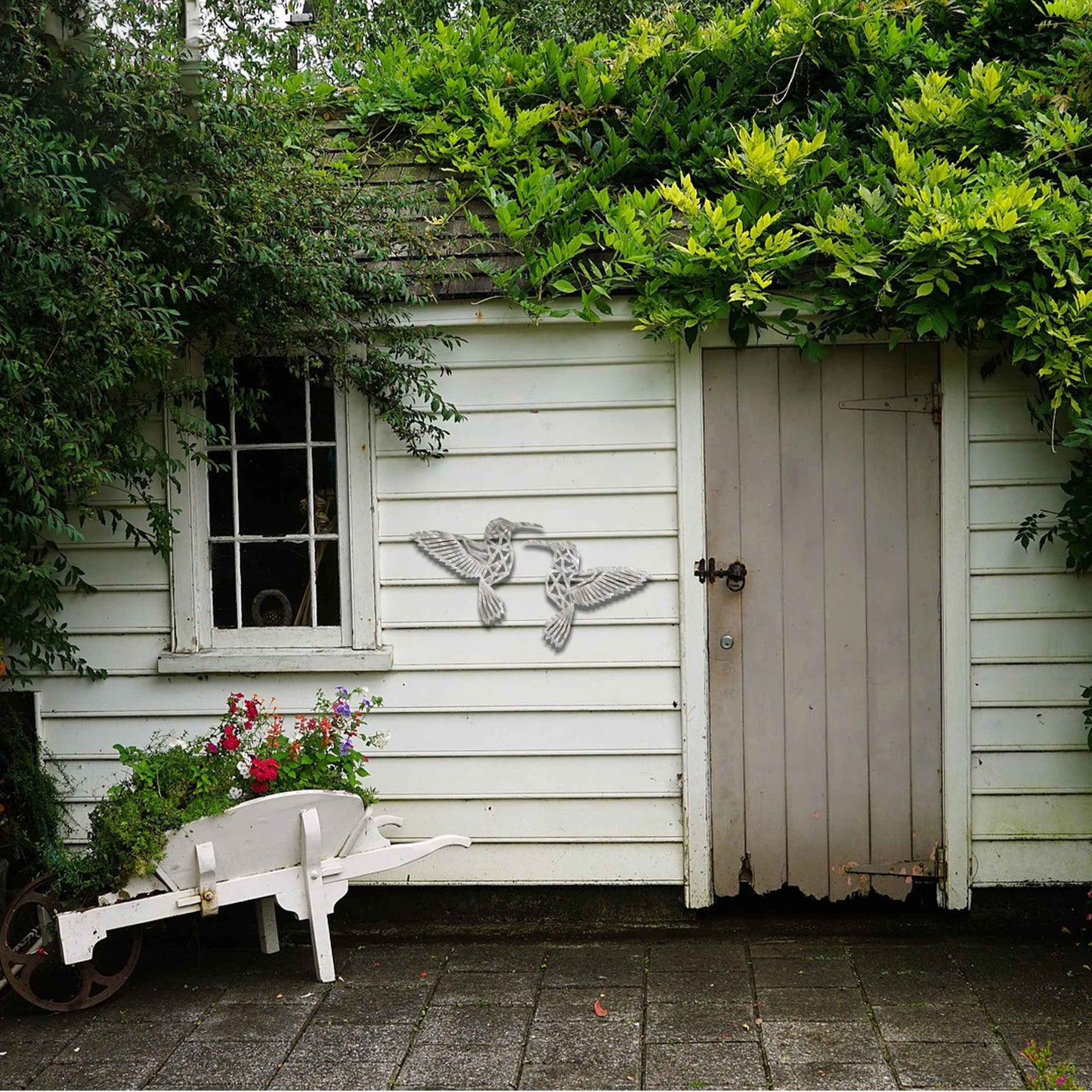 Metal garden decoration featuring two hummingbirds with geometric patterns in a dynamic pose, intricately designed to add elegance and a nature-inspired artistic touch to outdoor walls, fences, or garden sheds