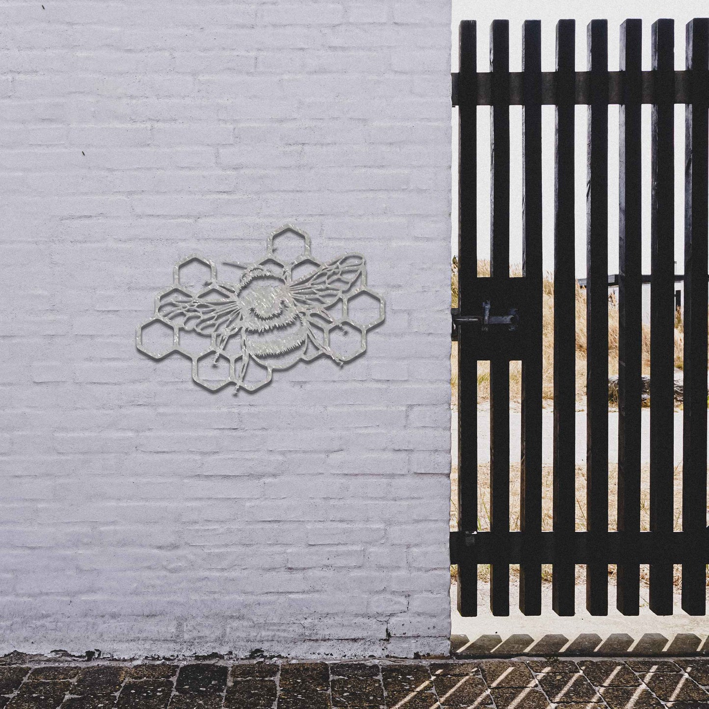 Metal garden decoration featuring a bee on a honeycomb design, showcasing intricate detailing in the wings and honeycomb structure, perfect for enhancing outdoor spaces with a nature-inspired artistic touch.