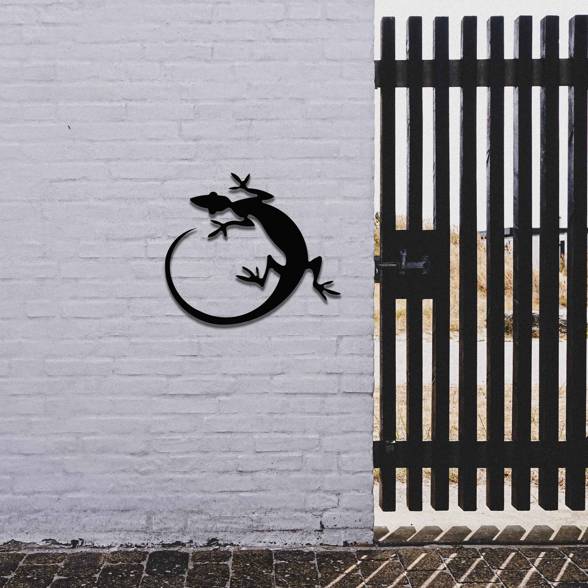 Metal garden decoration featuring a gecko silhouette design with a curved tail, adding a sleek and contemporary accent to outdoor walls, seamlessly complementing rustic and minimalist spaces.