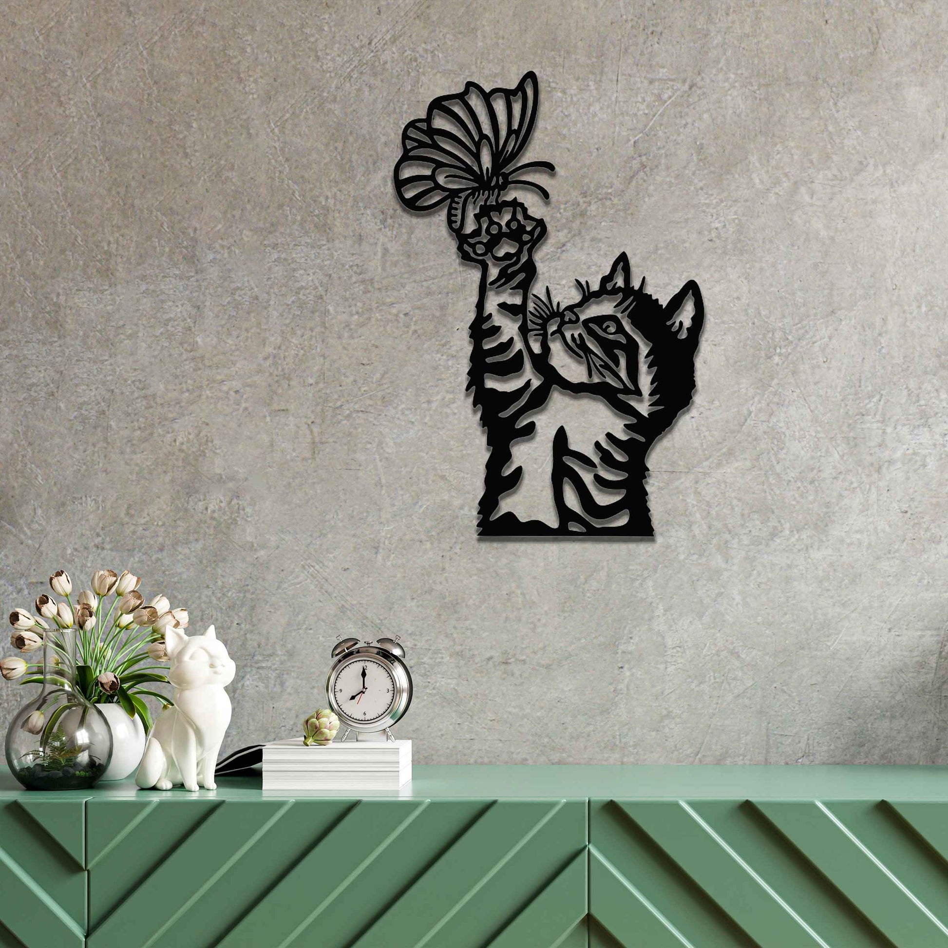 Metal wall art featuring a curious kitten playfully reaching for a butterfly, adding a delightful touch of charm and whimsy to modern indoor or outdoor decor, displayed on a neutral wall.
