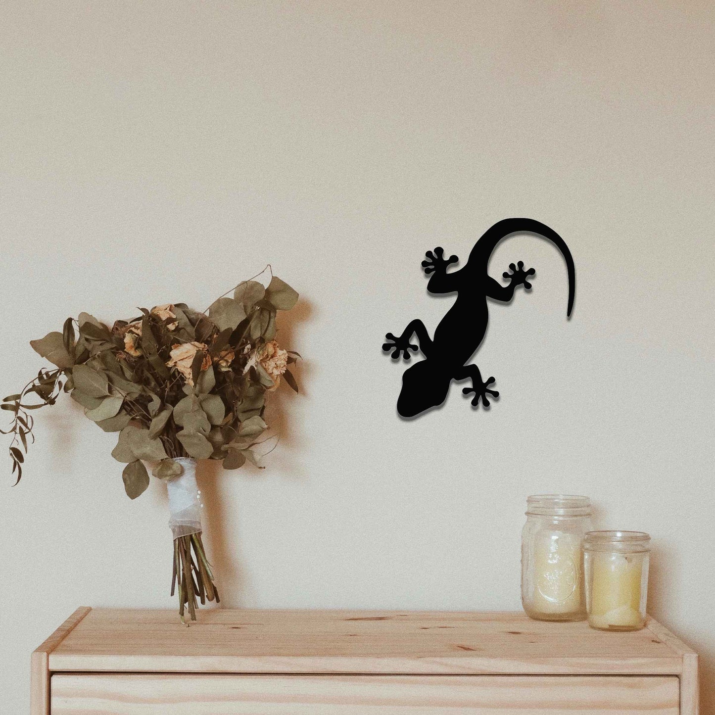 Metal wall decoration featuring a simple gecko silhouette design, adding a minimalist and modern touch to indoor spaces, displayed on a neutral wall within a contemporary decor setting.