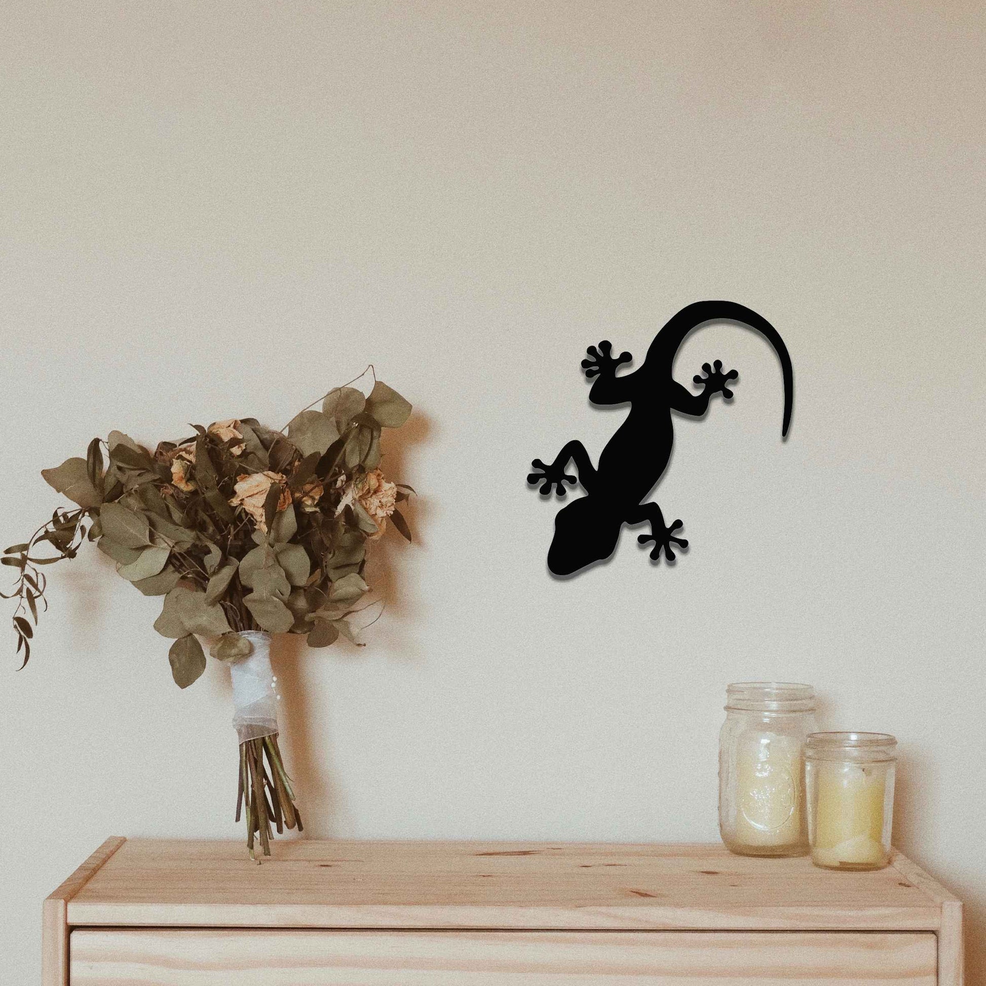 Metal wall decoration featuring a simple gecko silhouette design, adding a minimalist and modern touch to indoor spaces, displayed on a neutral wall within a contemporary decor setting.