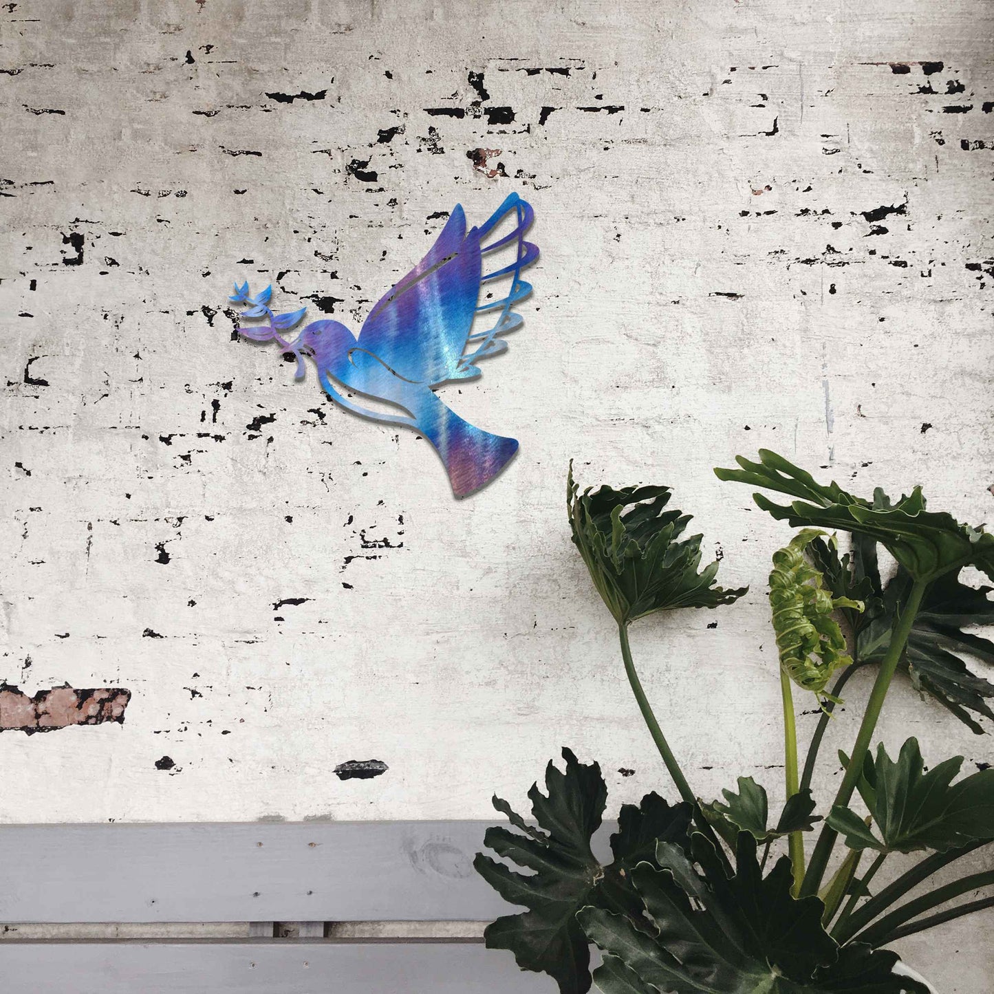 Metal garden decoration featuring a dove in flight holding an olive branch, crafted with a rustic finish, symbolising peace and harmony while adding a touch of elegance and meaning to outdoor spaces.