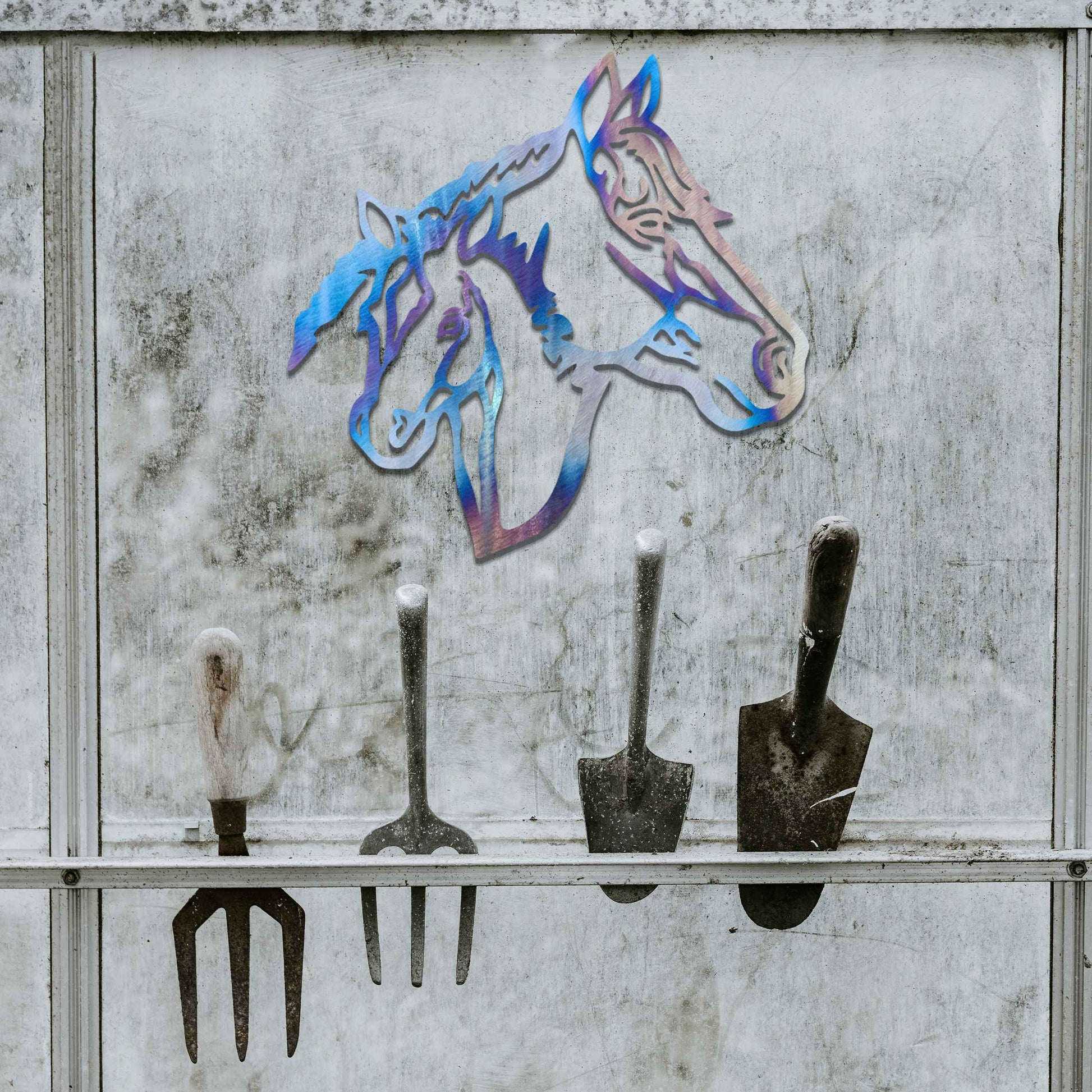 Metal wall art featuring the heads of two horses, one adult and one foal, side by side. The artwork is designed with bold, clean lines, emphasizing the intricate details of the horses' faces.