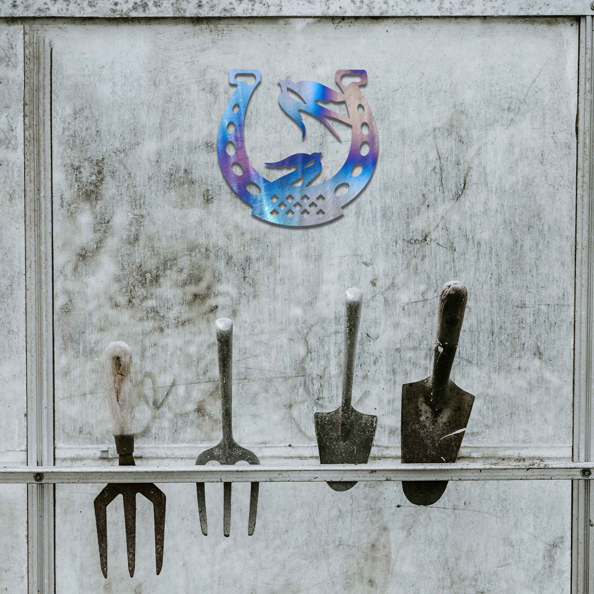 Metal garden decoration featuring two swallows perched within a horseshoe design, crafted with intricate detailing to symbolise luck and harmony, adding a rustic and charming touch to outdoor walls or fences.