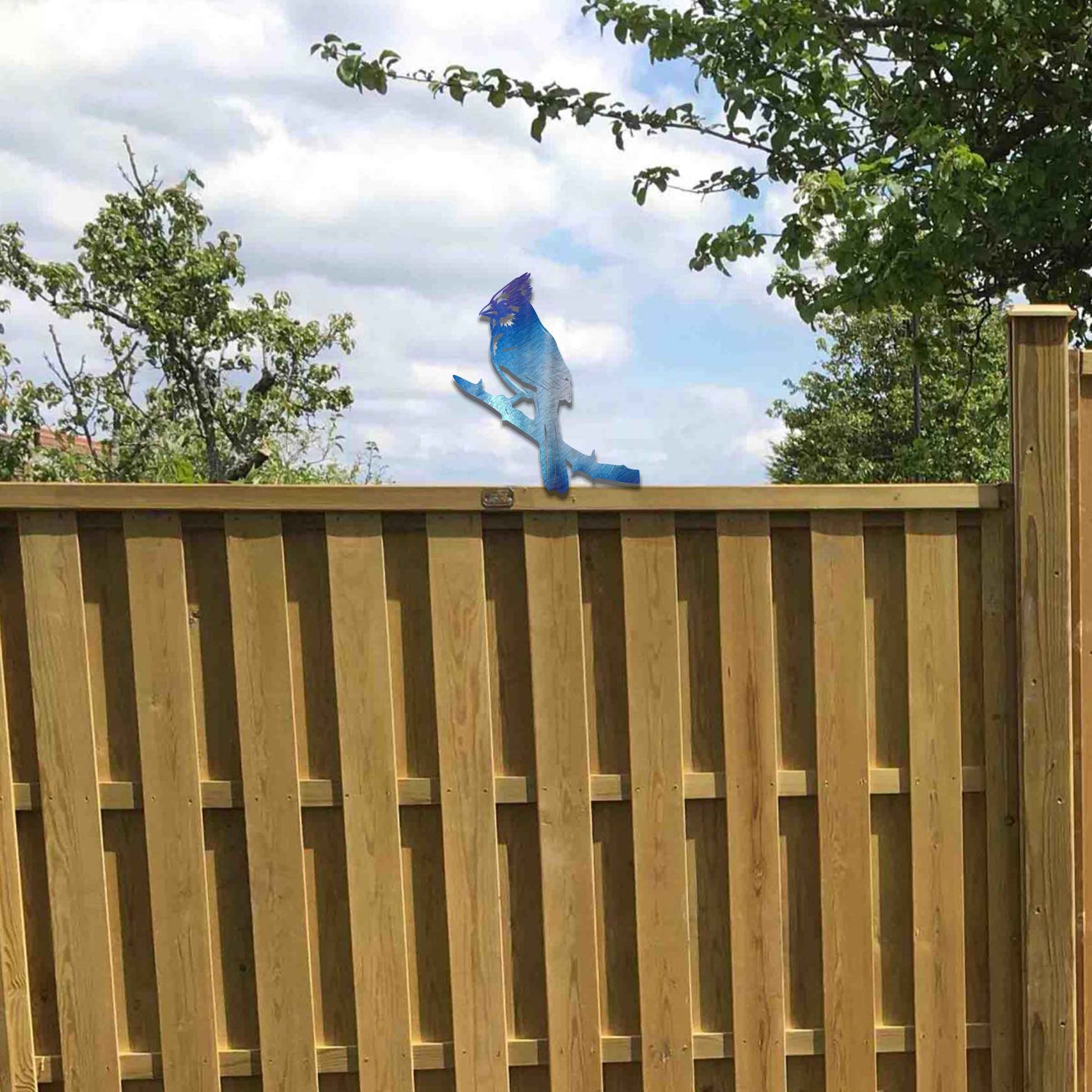 Metal garden decoration featuring a cardinal perched on a branch with intricate cutout details and a rustic finish, designed to enhance wooden fences or gates, adding a striking and natural accent to outdoor spaces.