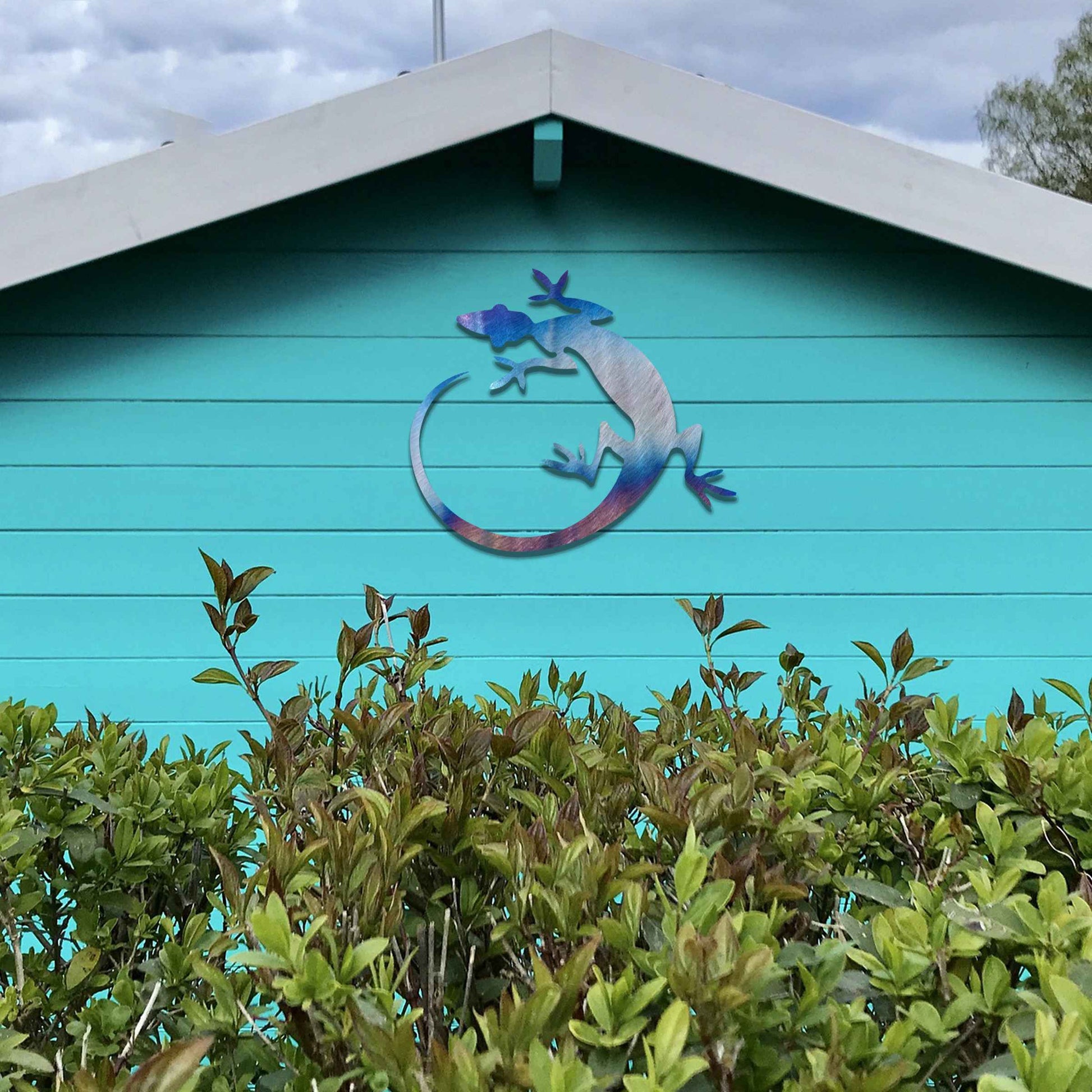 Metal garden decoration featuring a gecko silhouette design with a curved tail, adding a sleek and contemporary accent to outdoor walls, seamlessly complementing rustic and minimalist spaces.